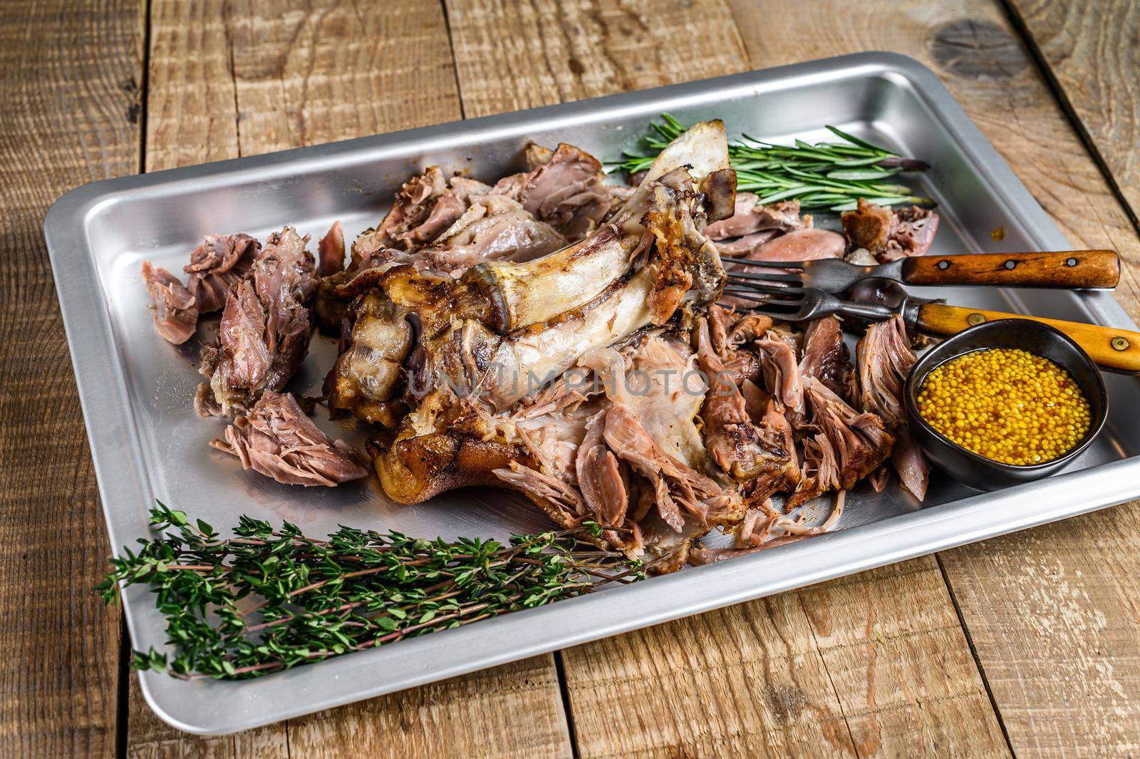 Roast pork knuckle eisbein meat on a baking pan with herbs. Wooden background. Top view by Composter