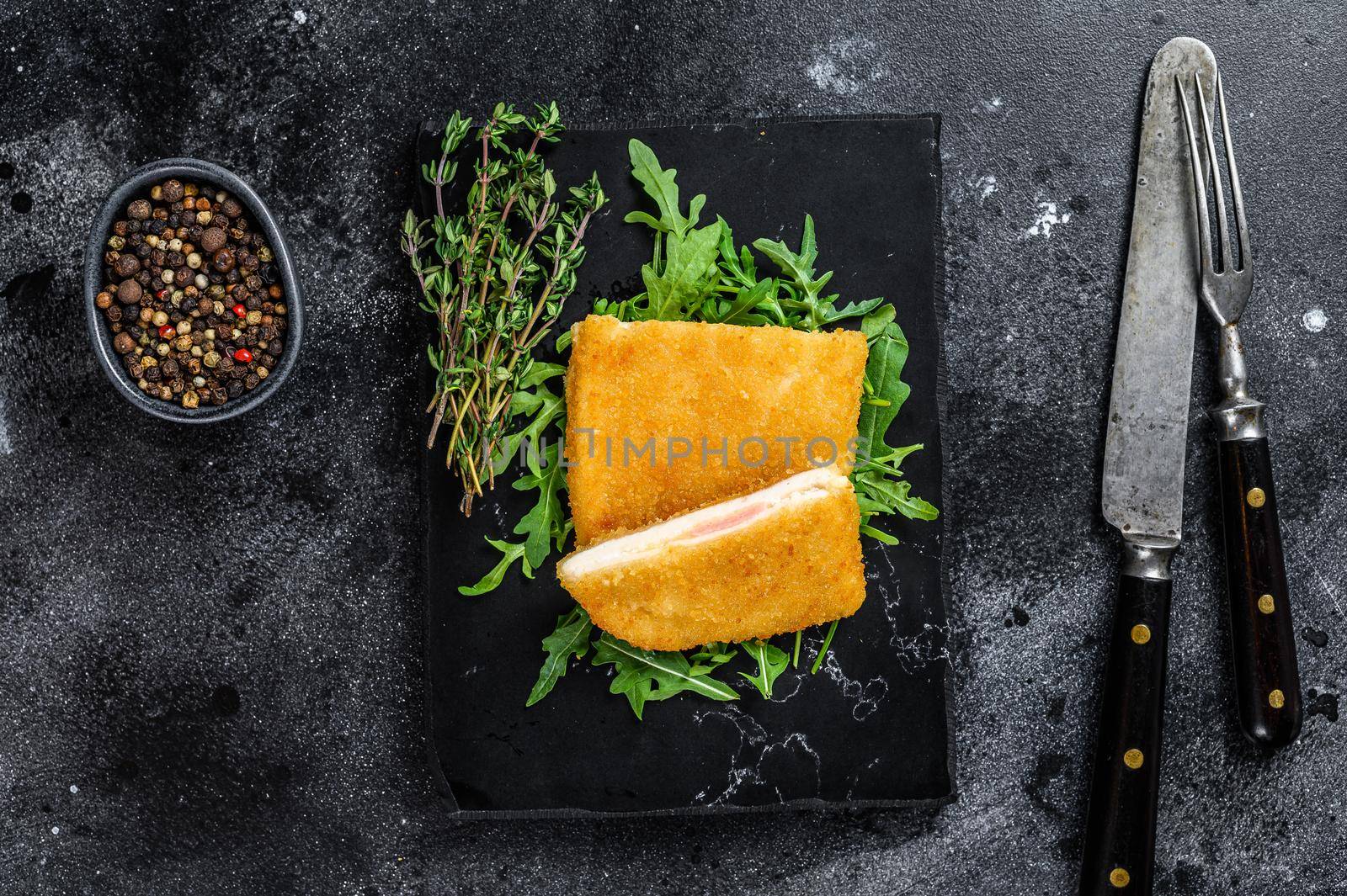 Fried cordon bleu meat chicken cutlet with ham and cheese. Black background. Top view.