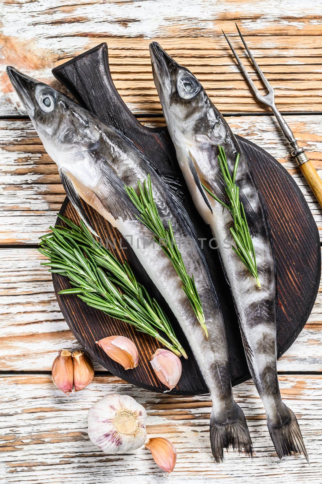 Raw whole icefish with herbs. White Wooden background. Top view.