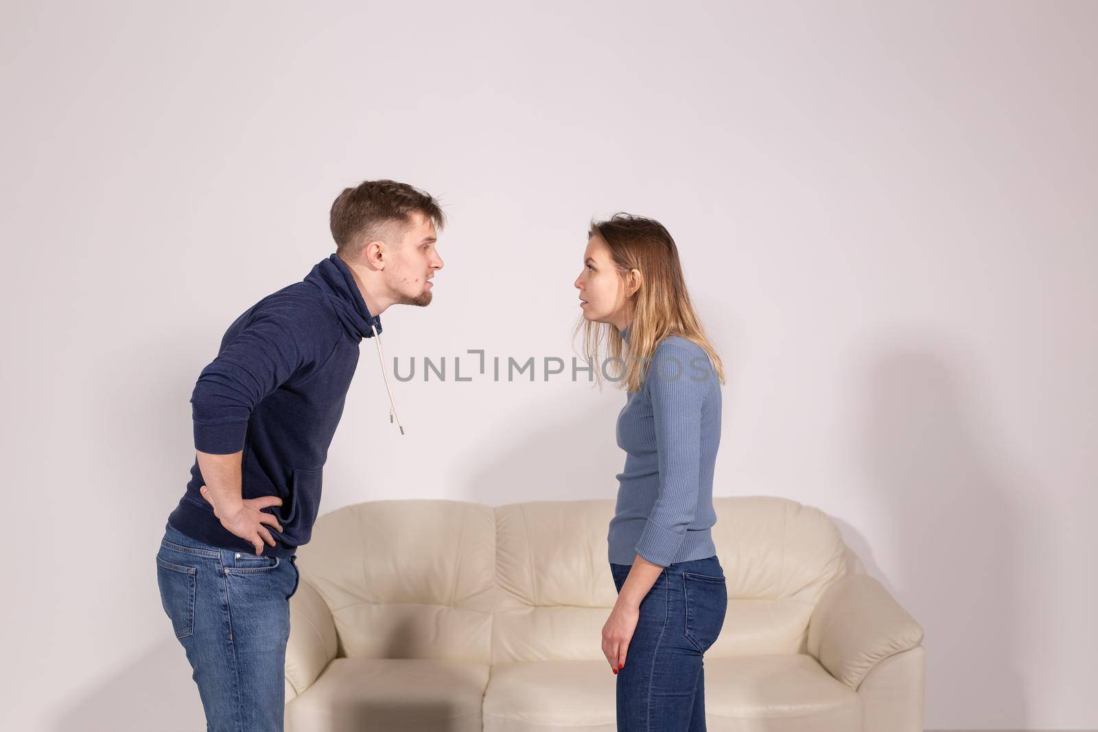 people, home violence and abuse concept - young couple screaming to each other on white background.