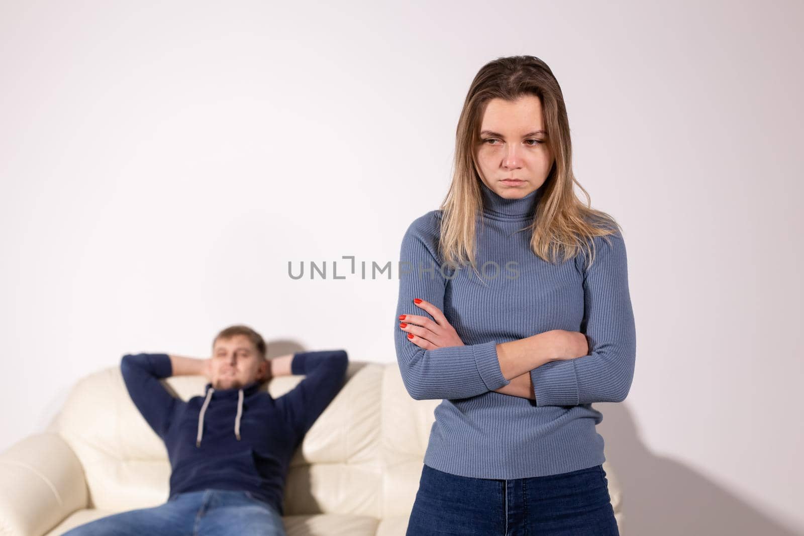 People, domestic violence and abuse concept - Woman with crossed arms and man on the white sofa by Satura86