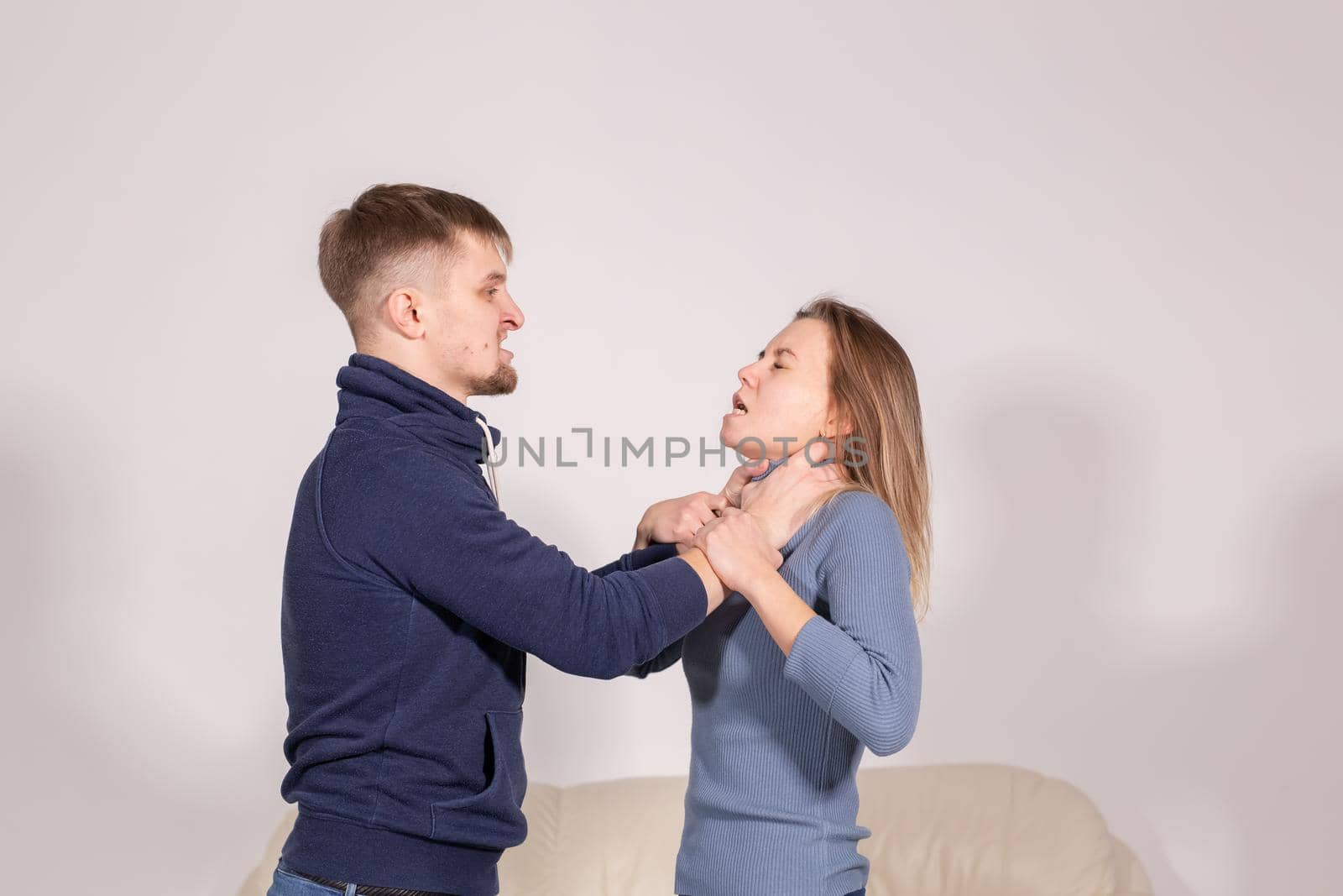 people, domestic violence and abuse concept - young man choked his wife on white background.