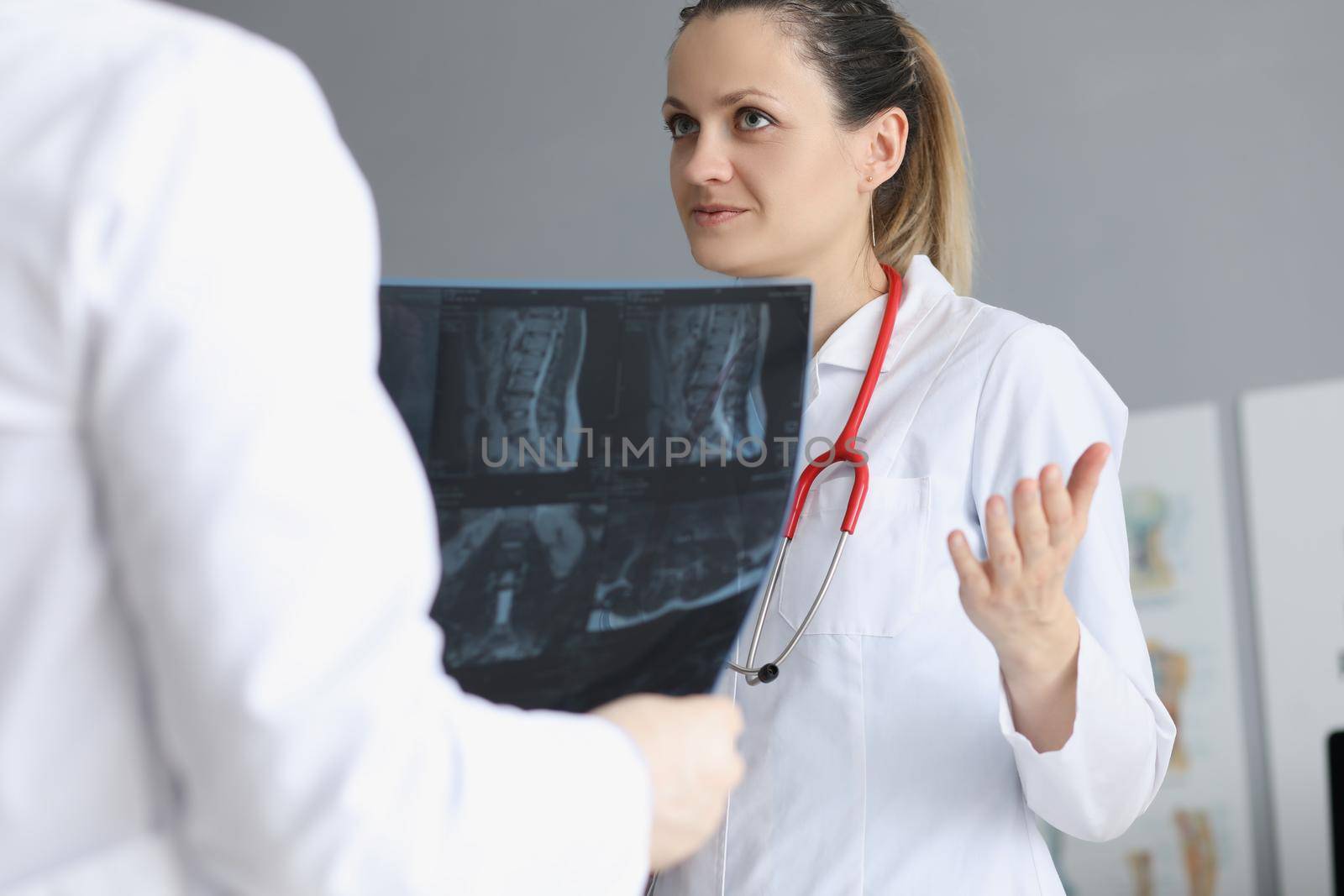 Portrait of female doctor deliberate with colleague about patients medical history. Worker hold scan result of clients checkup. Medicine, treatment concept