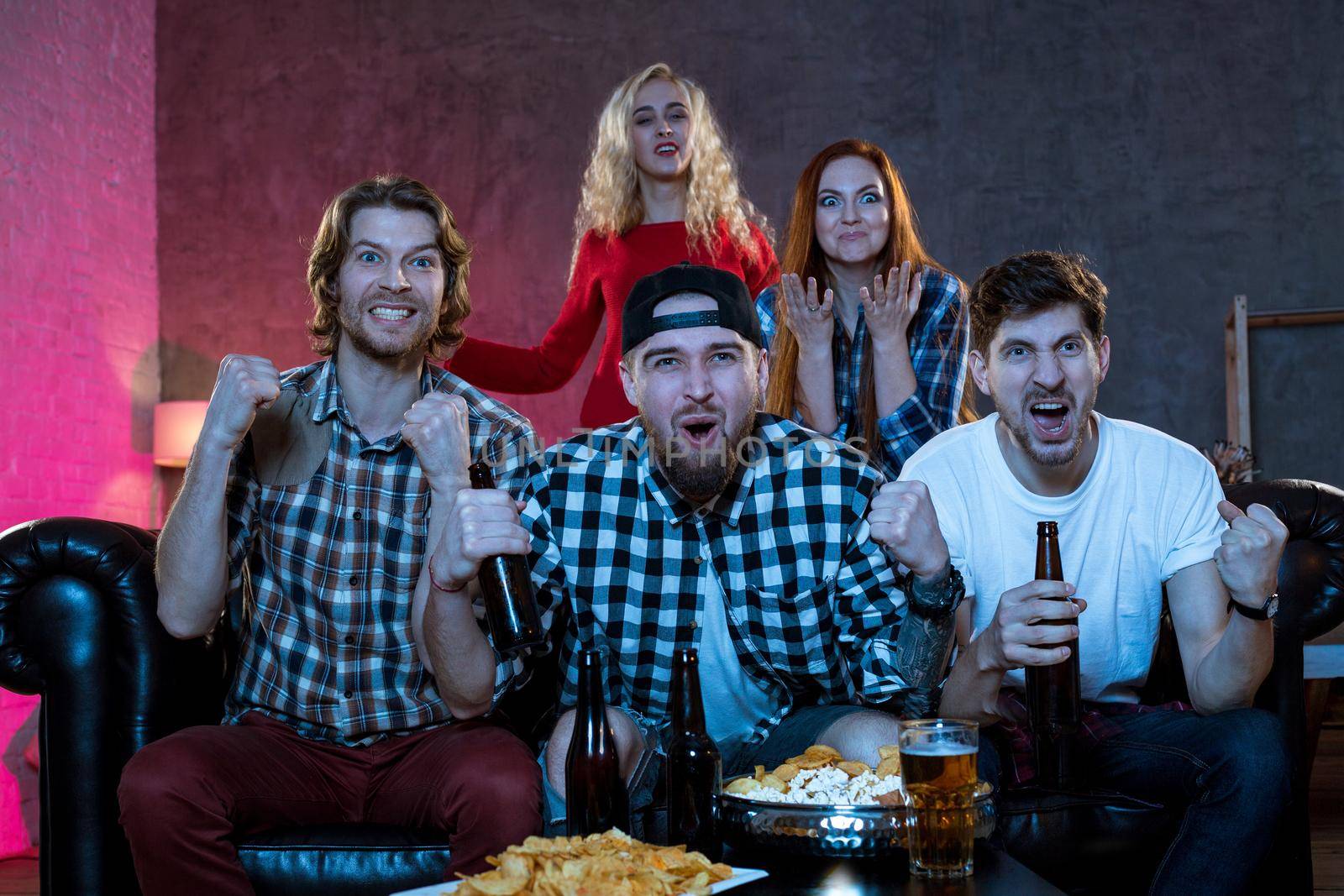 Group of friends watching TV match at home. Football fans on the couch