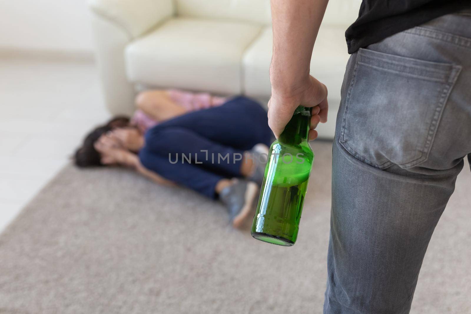 Victim, domestic violence, abuse and alcoholic concept - drunk man with bottle near his wife lying on the floor by Satura86