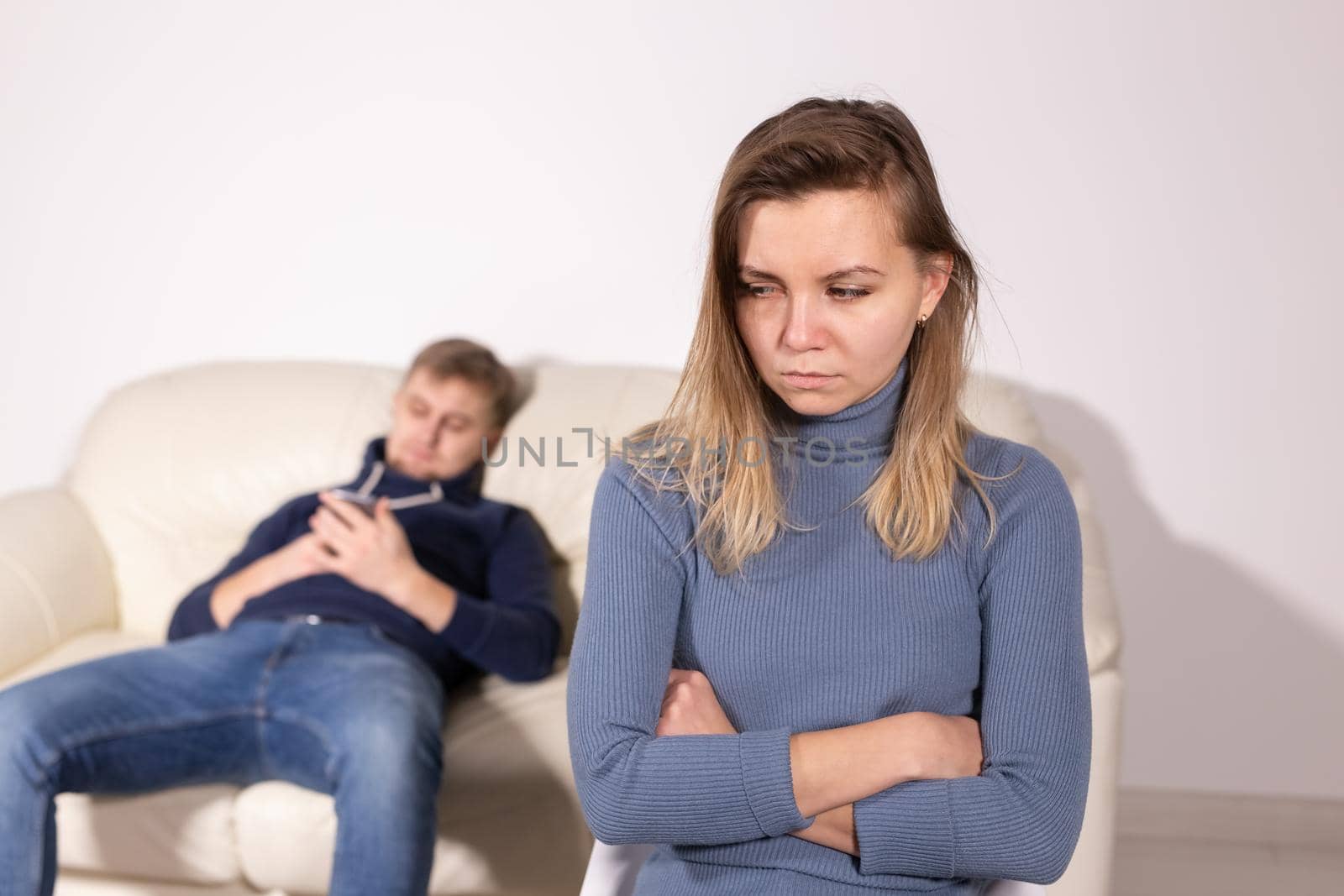 People, domestic violence and abuse concept - Woman with crossed arms and man on the white sofa by Satura86