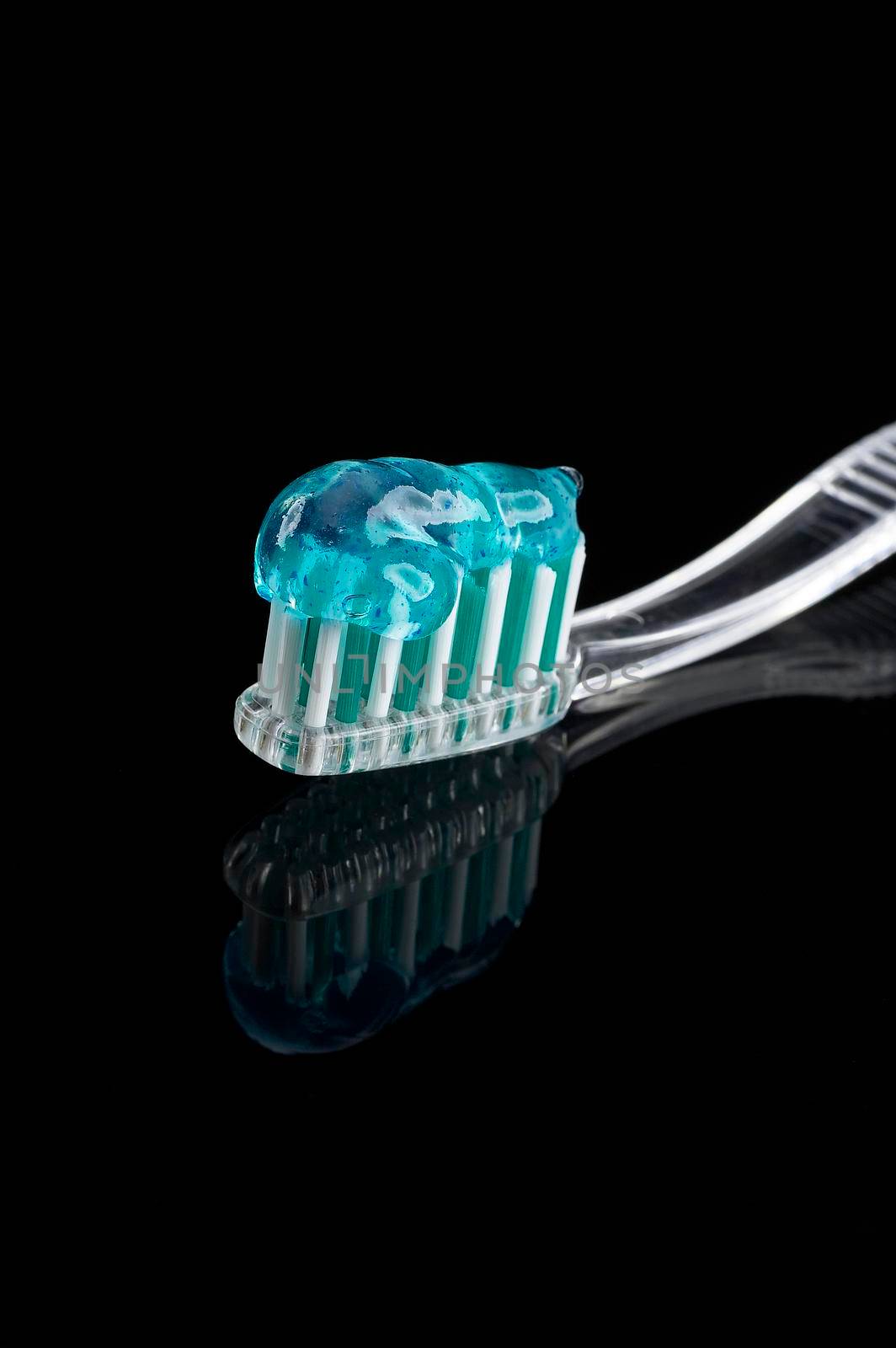 toothbrush and paste over black reflective background