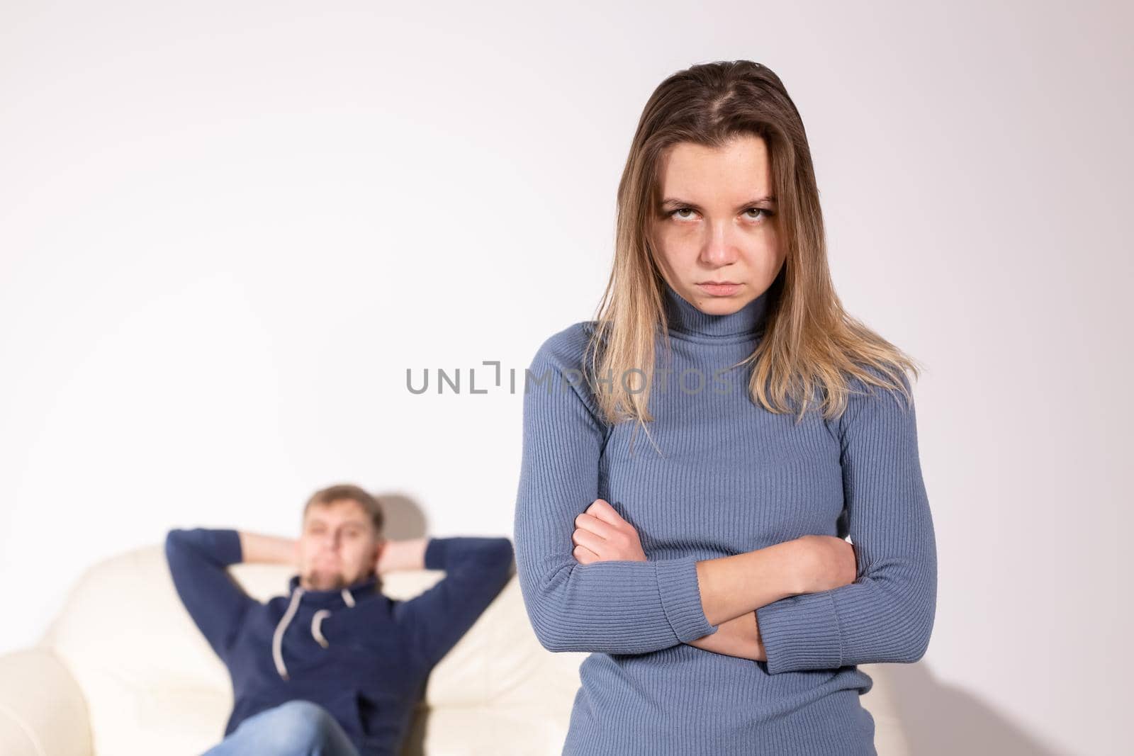 People, domestic violence and abuse concept - Woman with crossed arms and man on the white sofa.