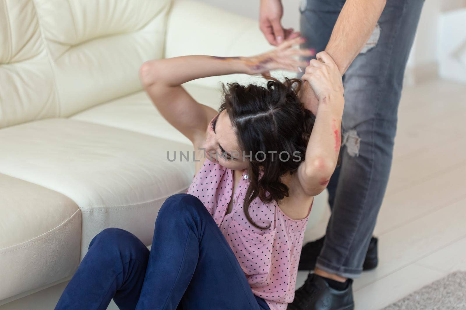 domestic violence, victim and abuse concept - cruel aggressive man grabbing his wife lying on the floor.