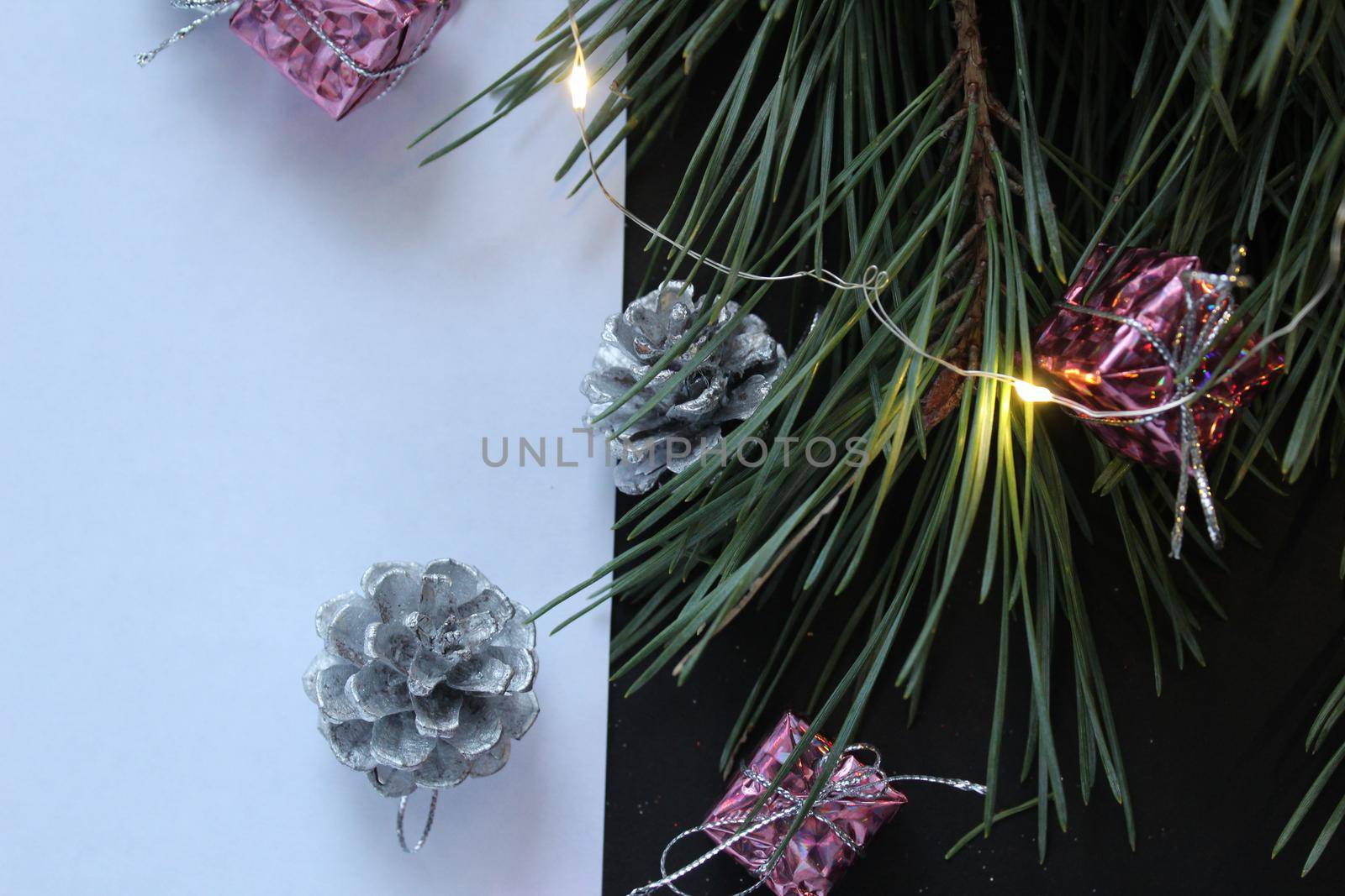 a white sheet of paper next to a branch of its pine tree next to a garland cone with space for text and with copyspace.