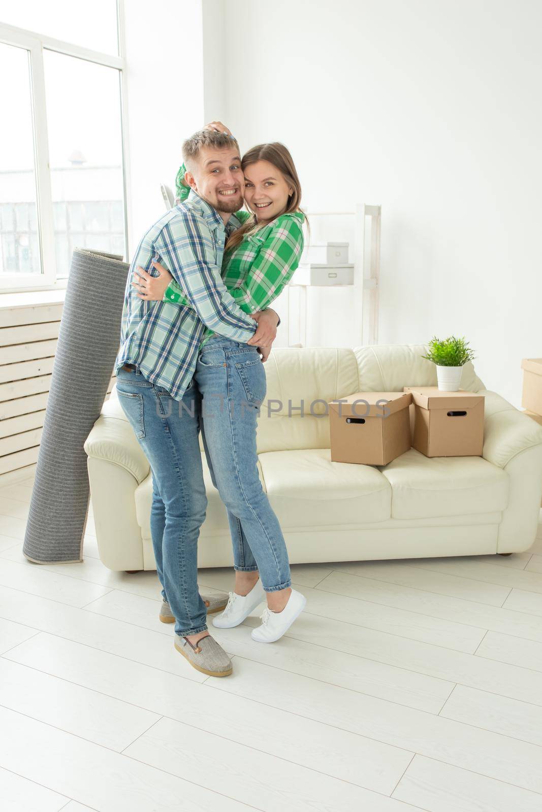 Loving young couple embracing rejoicing in moving to their new home. The concept of moving and housewarming of young family. by Satura86