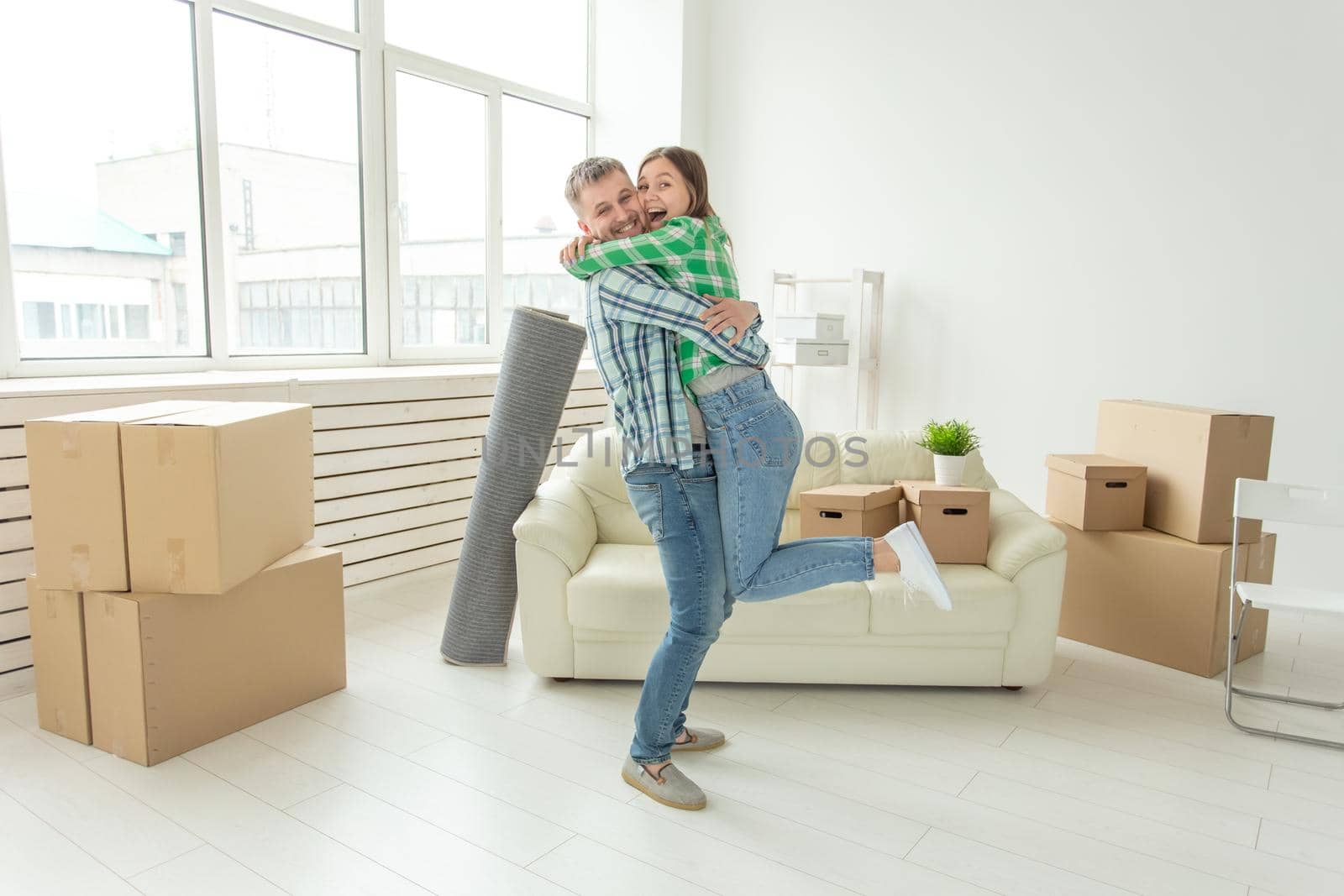 Young couple in denim pants embracing rejoicing in their new apartment during the move. The concept of housewarming and credit for new housing