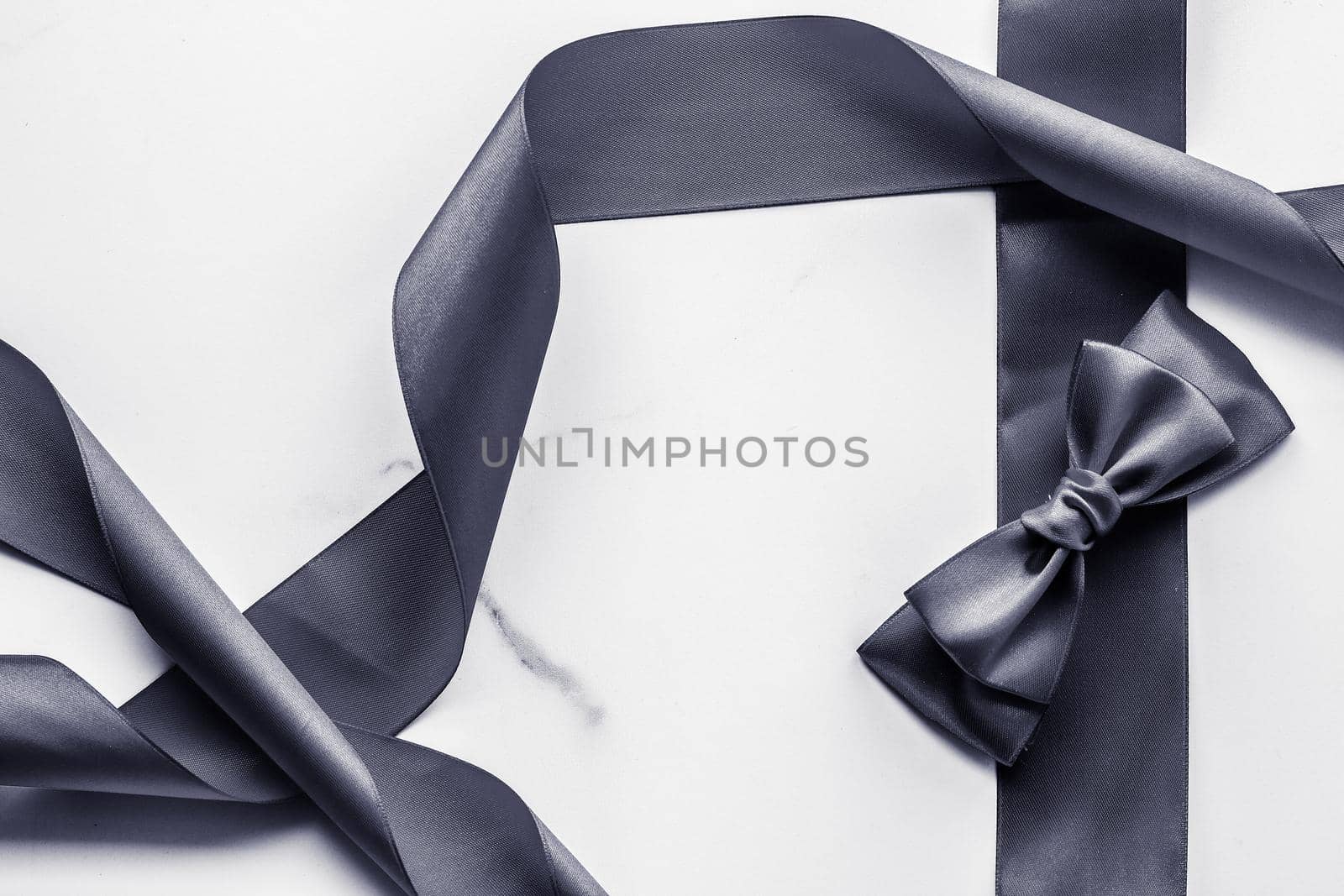 Holiday gift, decoration and sale promotion concept - Black silk ribbon and bow on marble background, flatlay