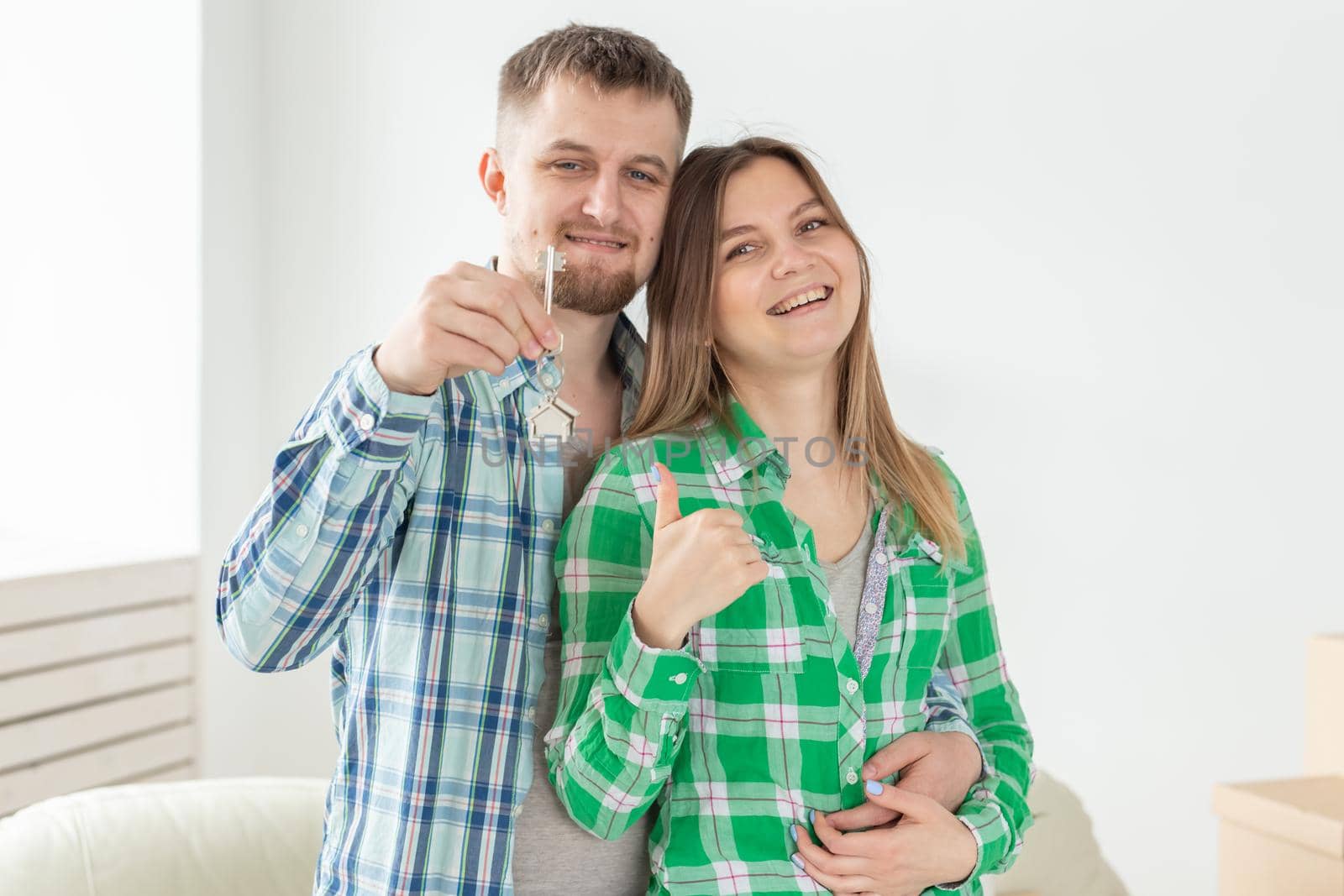 Young married couple with boxes and holding flat keys