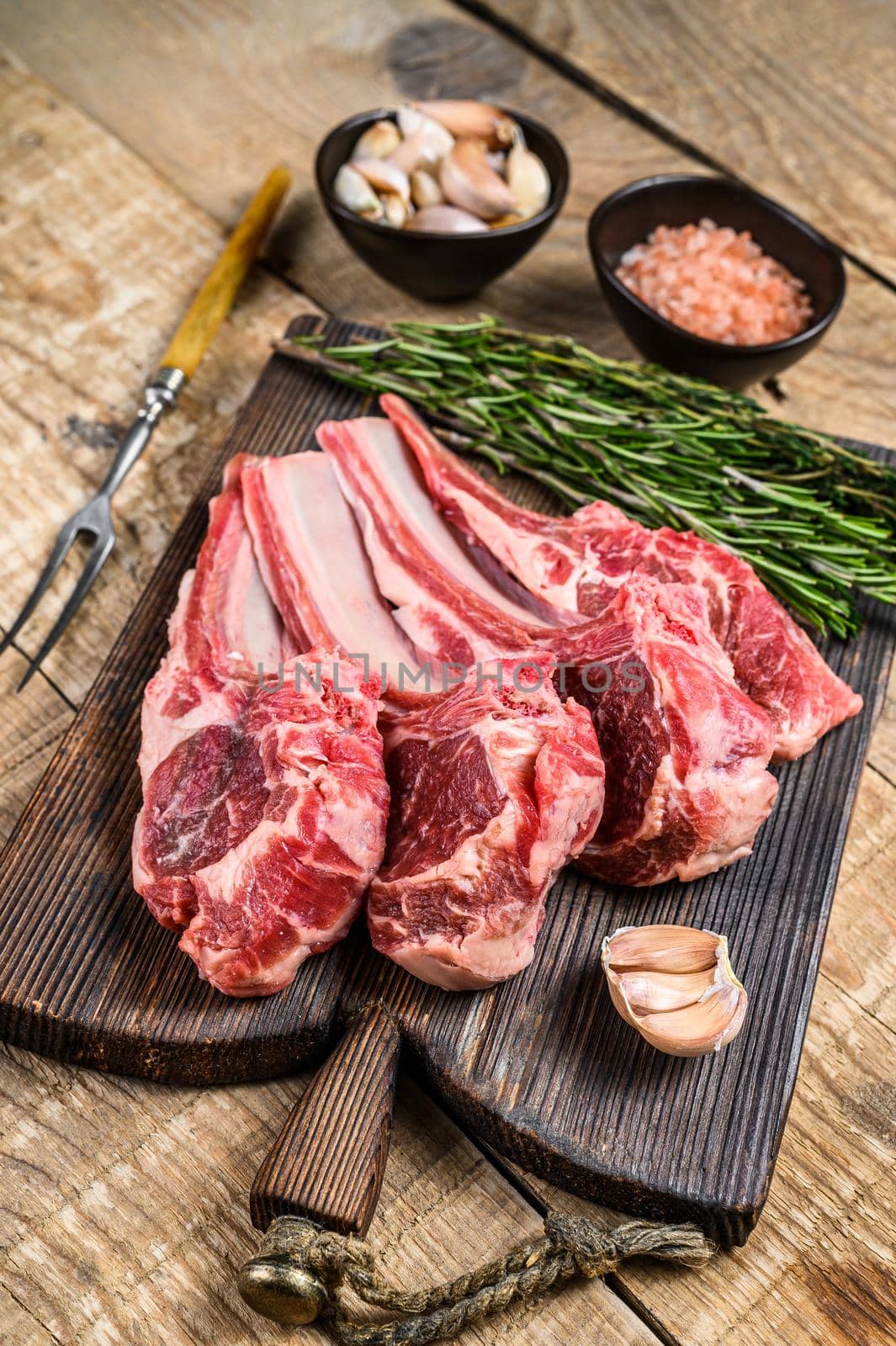 Lamb raw cutlets chops with salt, pepper and garlic. wooden background. Top view by Composter
