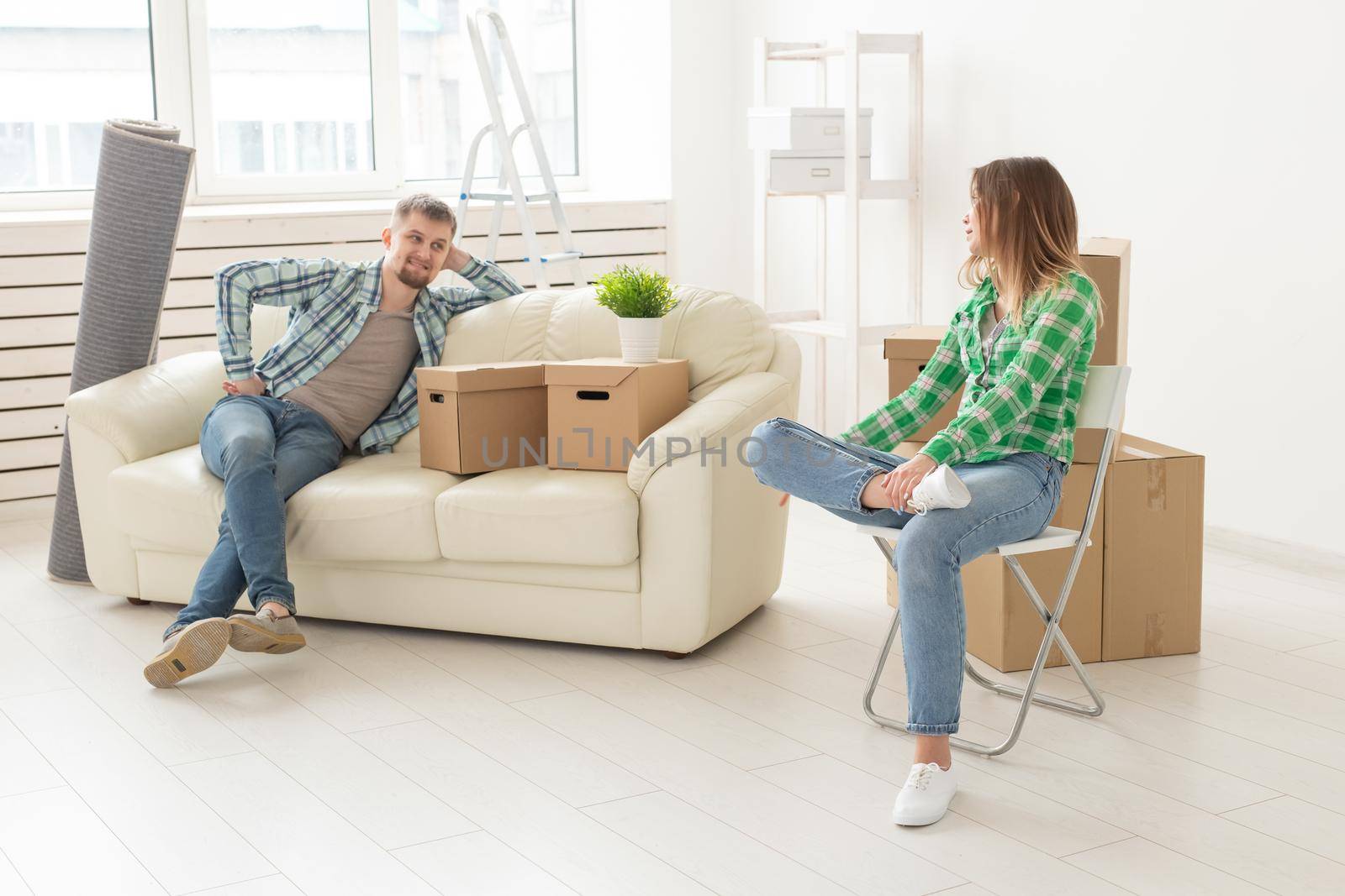 Positive smiling young girl sitting against her laughing in a new living room while moving to a new home. The concept of joy from the possibility of finding new housing. by Satura86