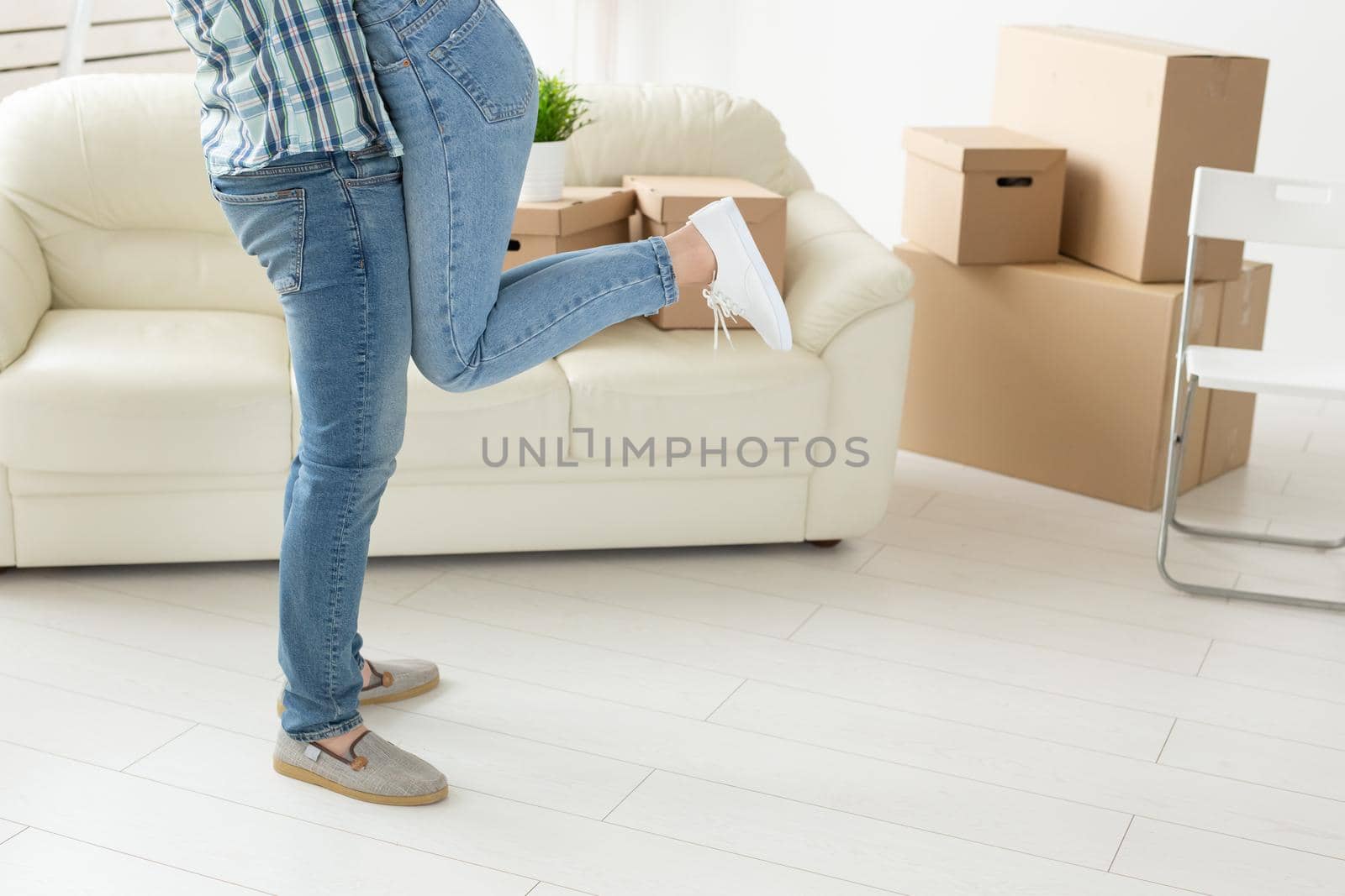 Unidentified young couple in denim pants embracing rejoicing in their new apartment during the move. The concept of housewarming and credit for new housing