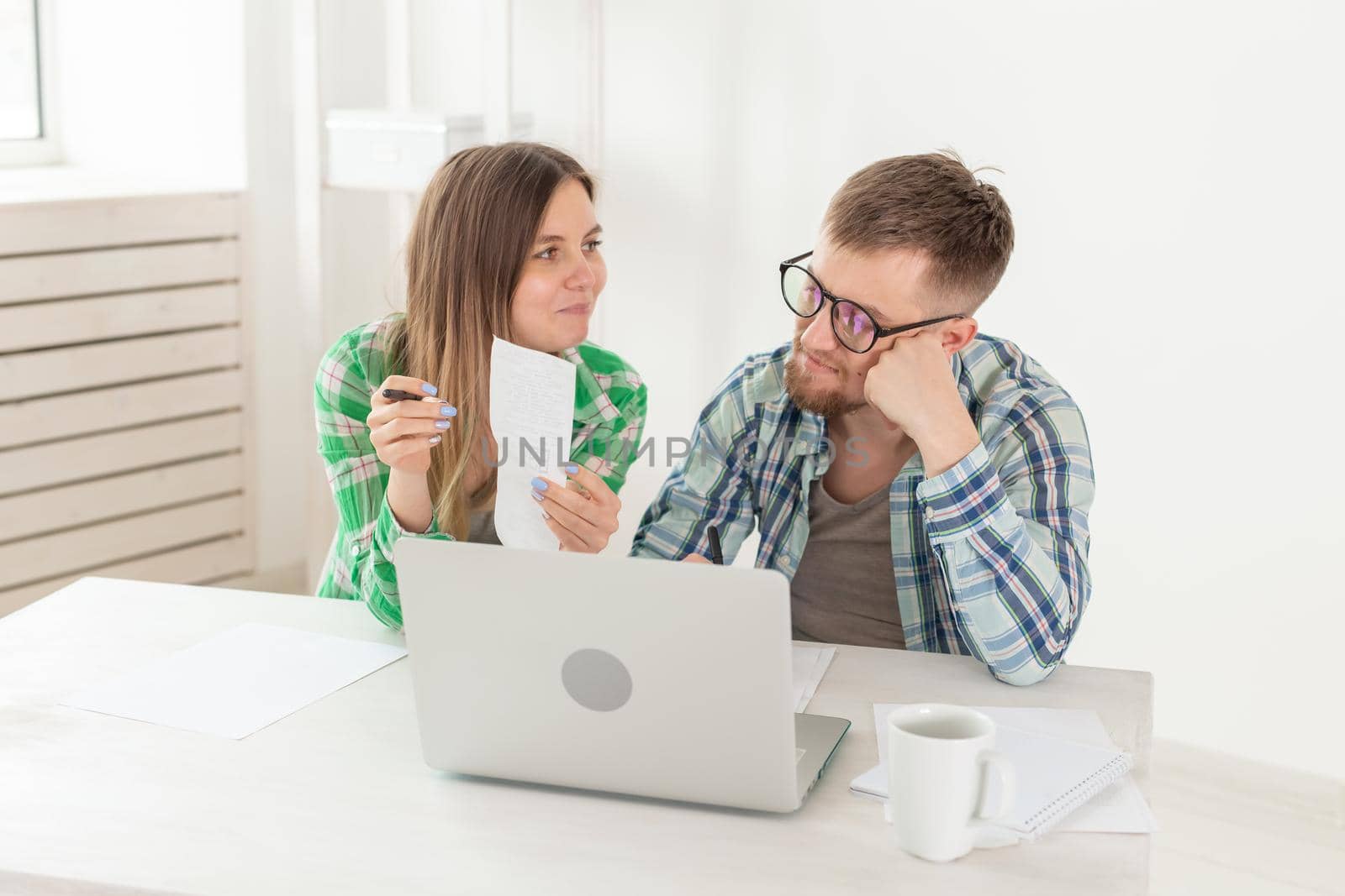 Surprised married couple. Husband and wife are considering bills for paying an apartment and are shocked at the amount received by writing down the results in their home accounting in a laptop