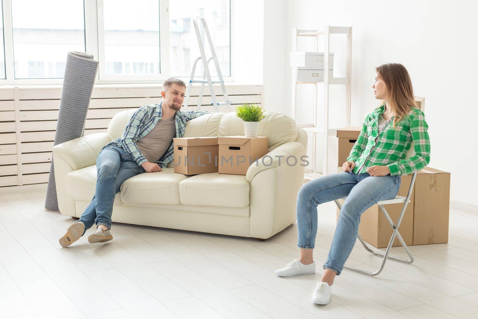 Positive smiling young girl sitting against her laughing in a new living room while moving to a new home. The concept of joy from the possibility of finding new housing