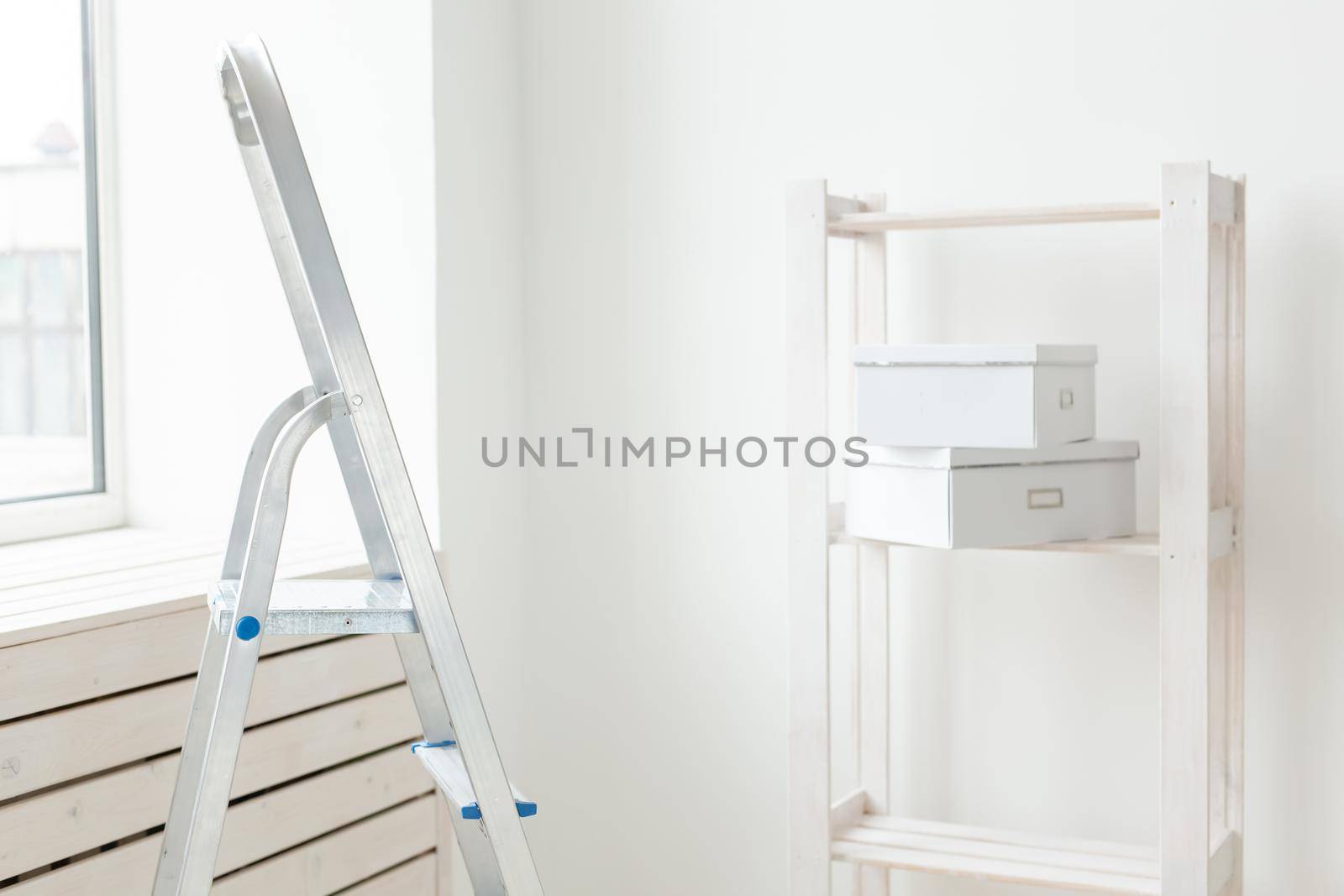 Stepladder and an empty shelf with boxes are in the new living room during the renovation after the move. The concept of housewarming and repair in new housing