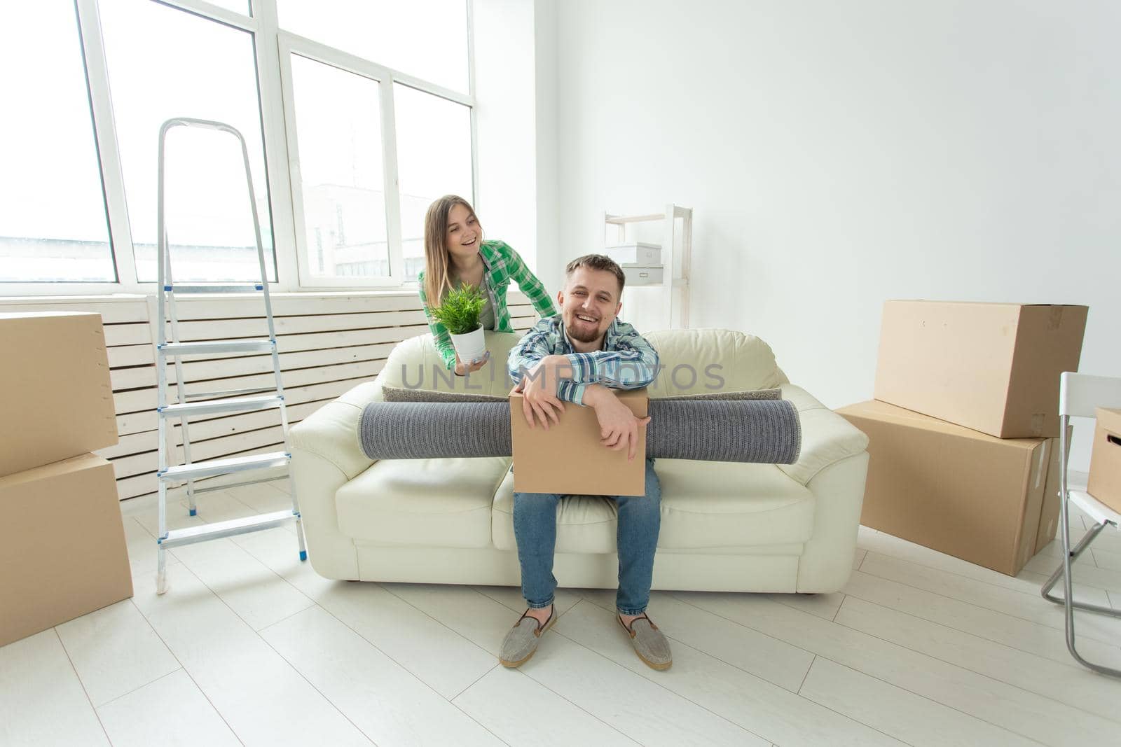Cheerful young couple rejoices in moving to a new home laying out their belongings in the living room. Concept of housewarming and mortgages for a young family.