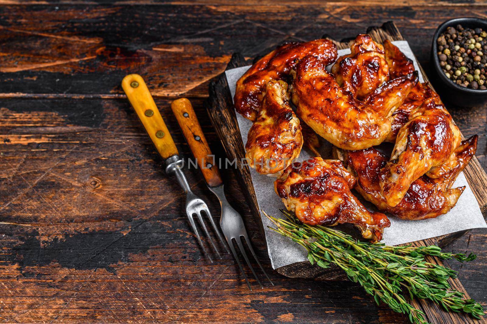 Baked Bbq chicken wings with dip sauce. Dark wooden background. Top view. Copy space.