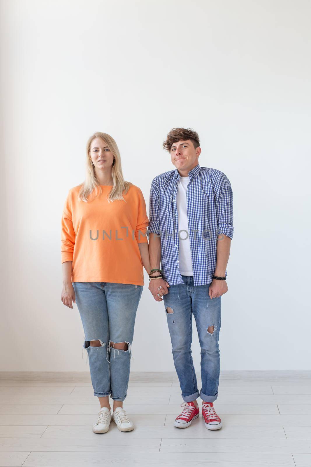 Portrait of a cheerful young positive couple in full growth dressed in casual clothes posing on a white background. Concept of stylish young modern people