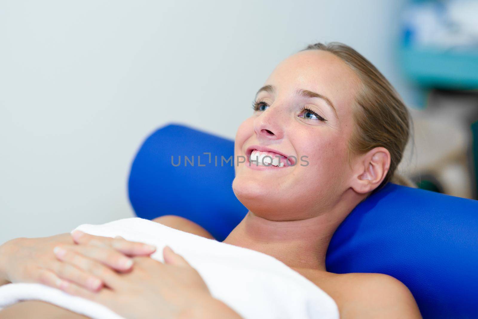 Young female patient on bed in a physiotherapy center. Blonde woman with blue eyes.