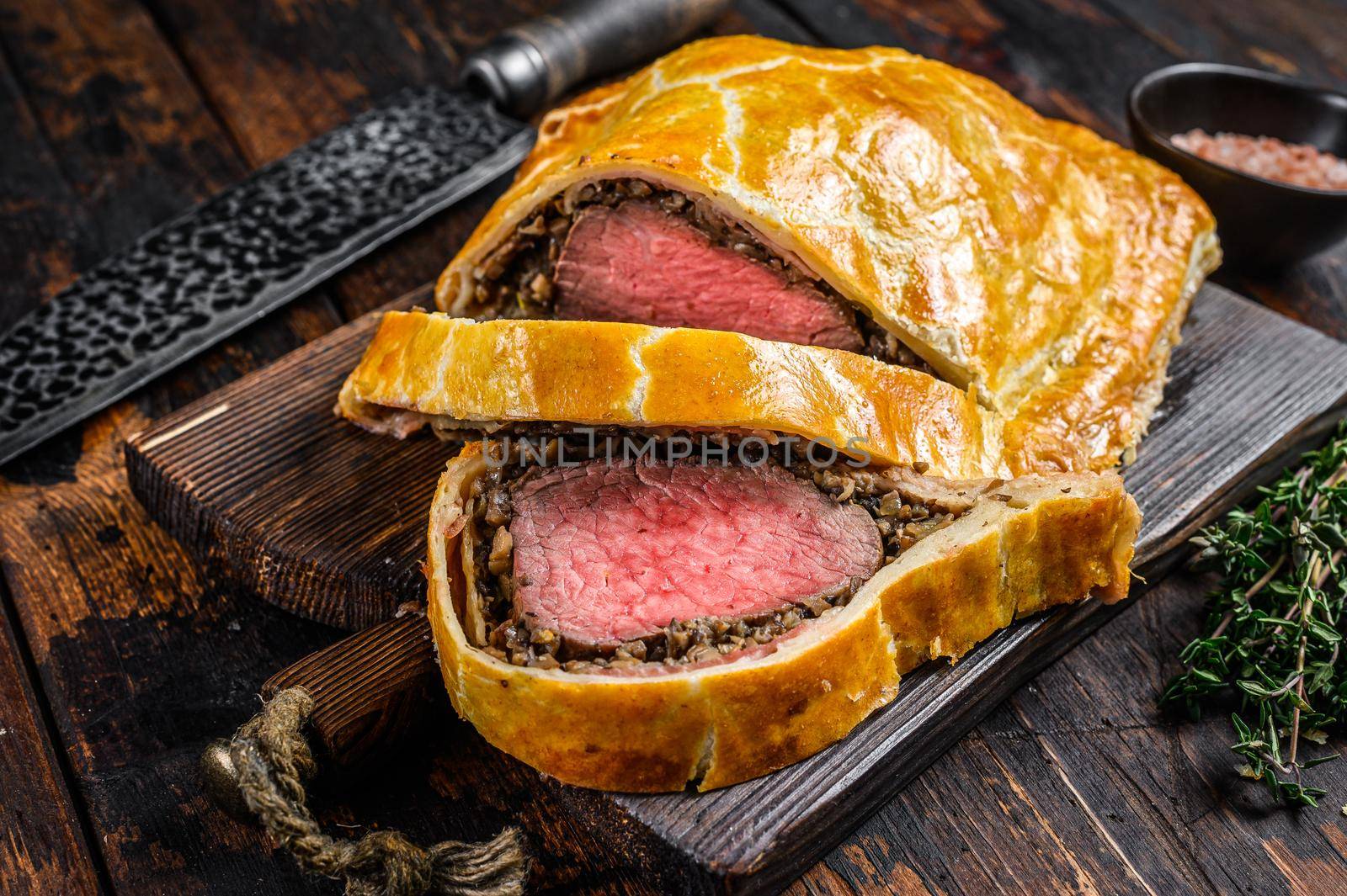 Homemade Beef Wellington puff pie with tenderloin meat on a cutting board. Dark wooden background. Top view by Composter