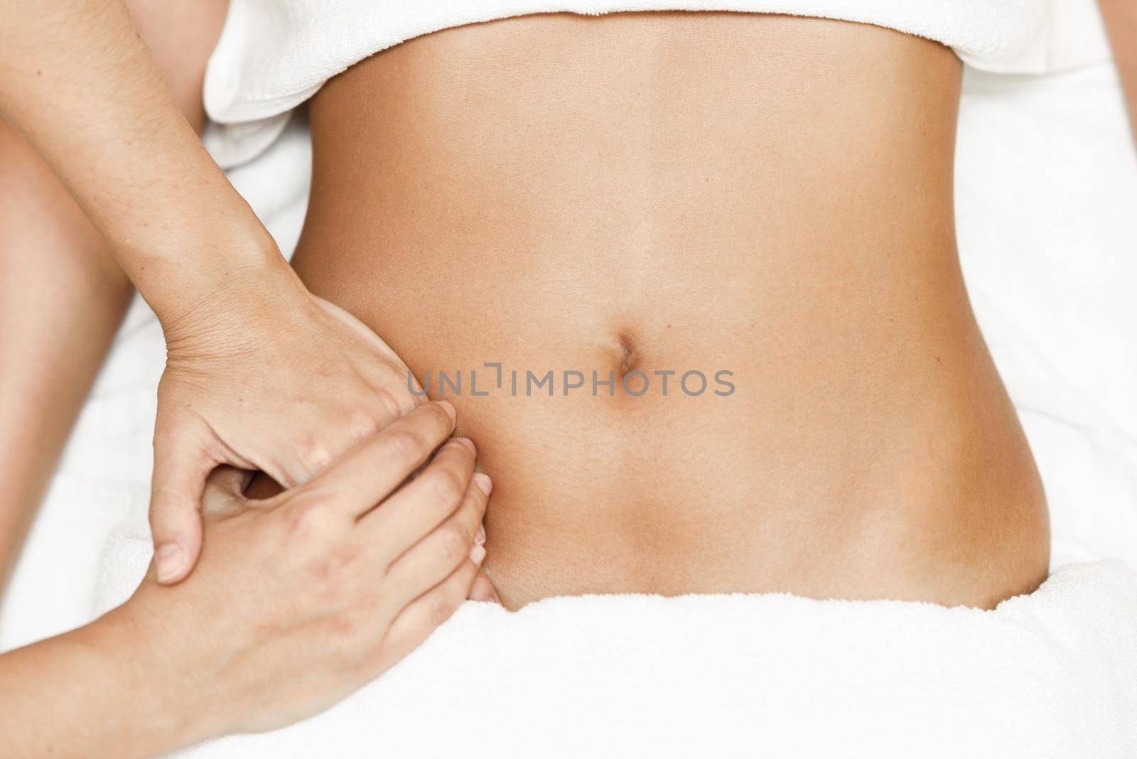 Top view of hands massaging female abdomen.Therapist applying pressure on belly. Woman receiving massage at spa salon