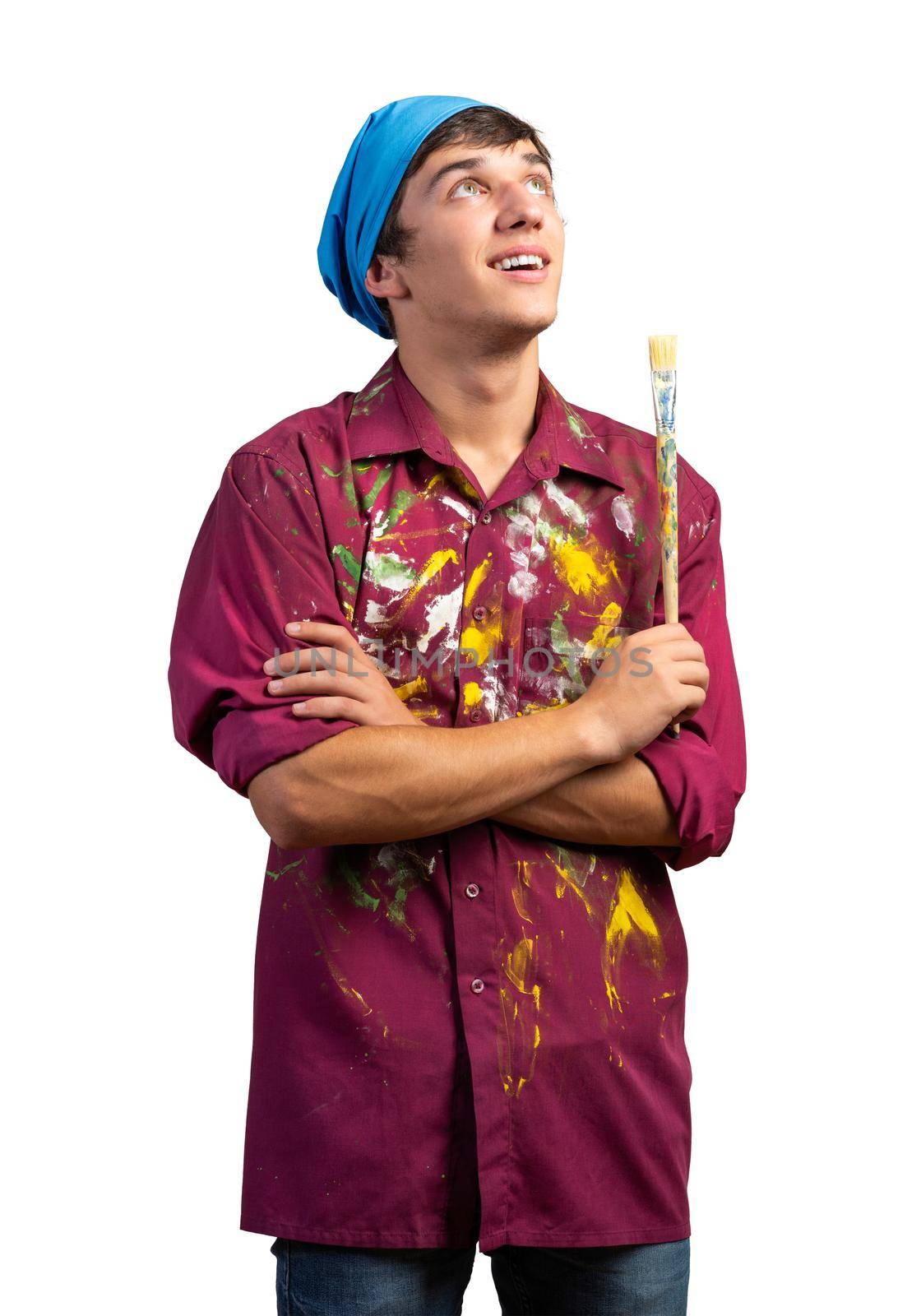 Smiling young painter artist holding paintbrush. Portrait of happy painter looking upwards isolated on white background. Creative hobby and artistic occupation. Art school student posing.