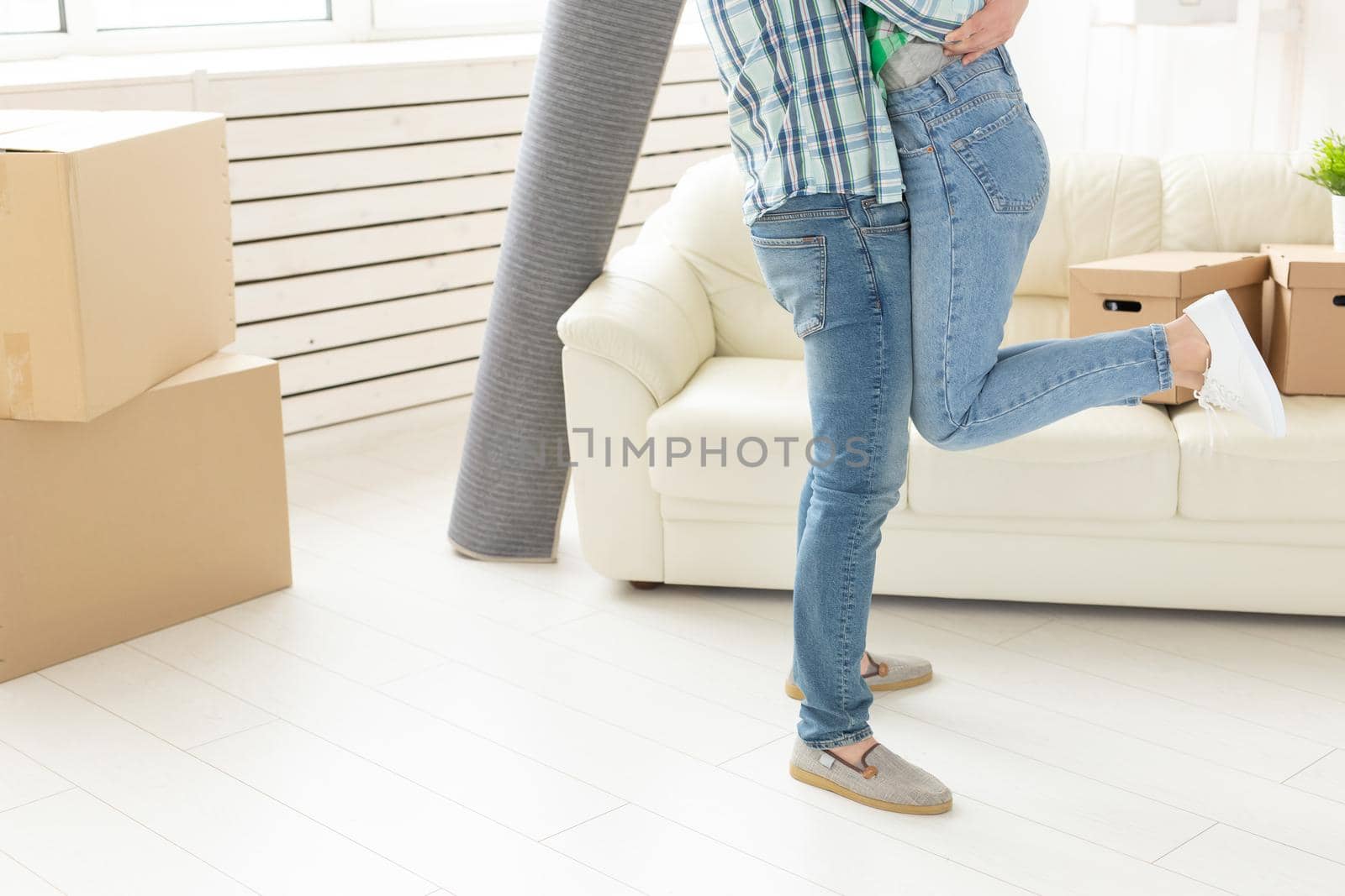 Unidentified young couple in denim pants embracing rejoicing in their new apartment during the move. The concept of housewarming and credit for new housing. by Satura86