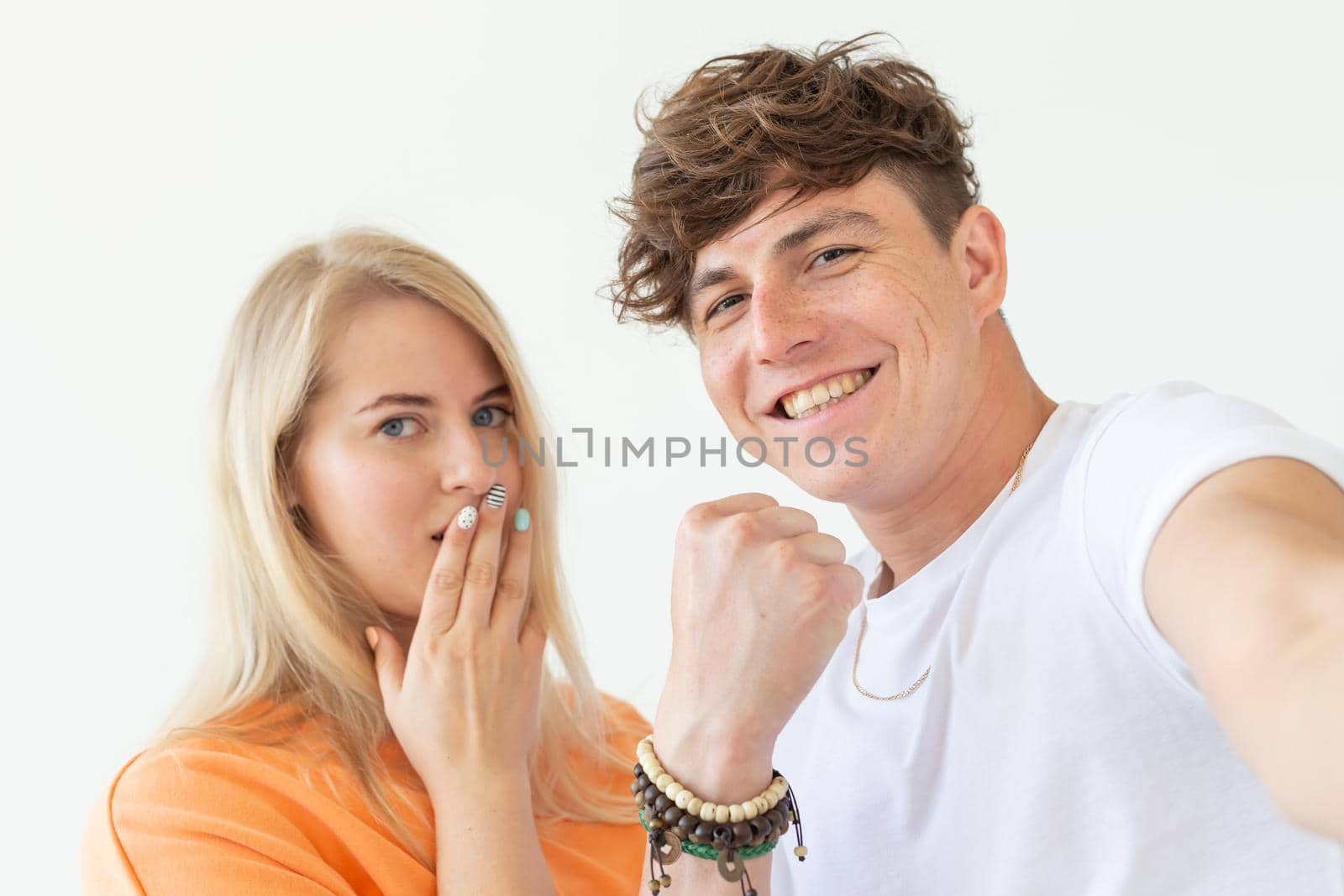 Charming young couple cute blond girl girl take a selfie posing over white background. Concept a young couple of teenagers or millennials In love