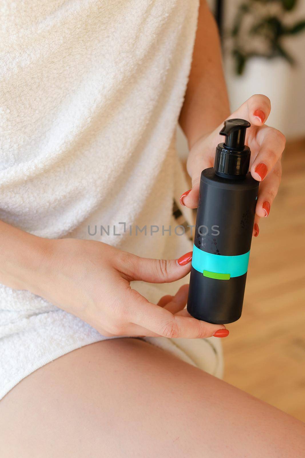 Beautiful fresh young woman applying cream or body wash on hand from dispenser indoors by sisterspro