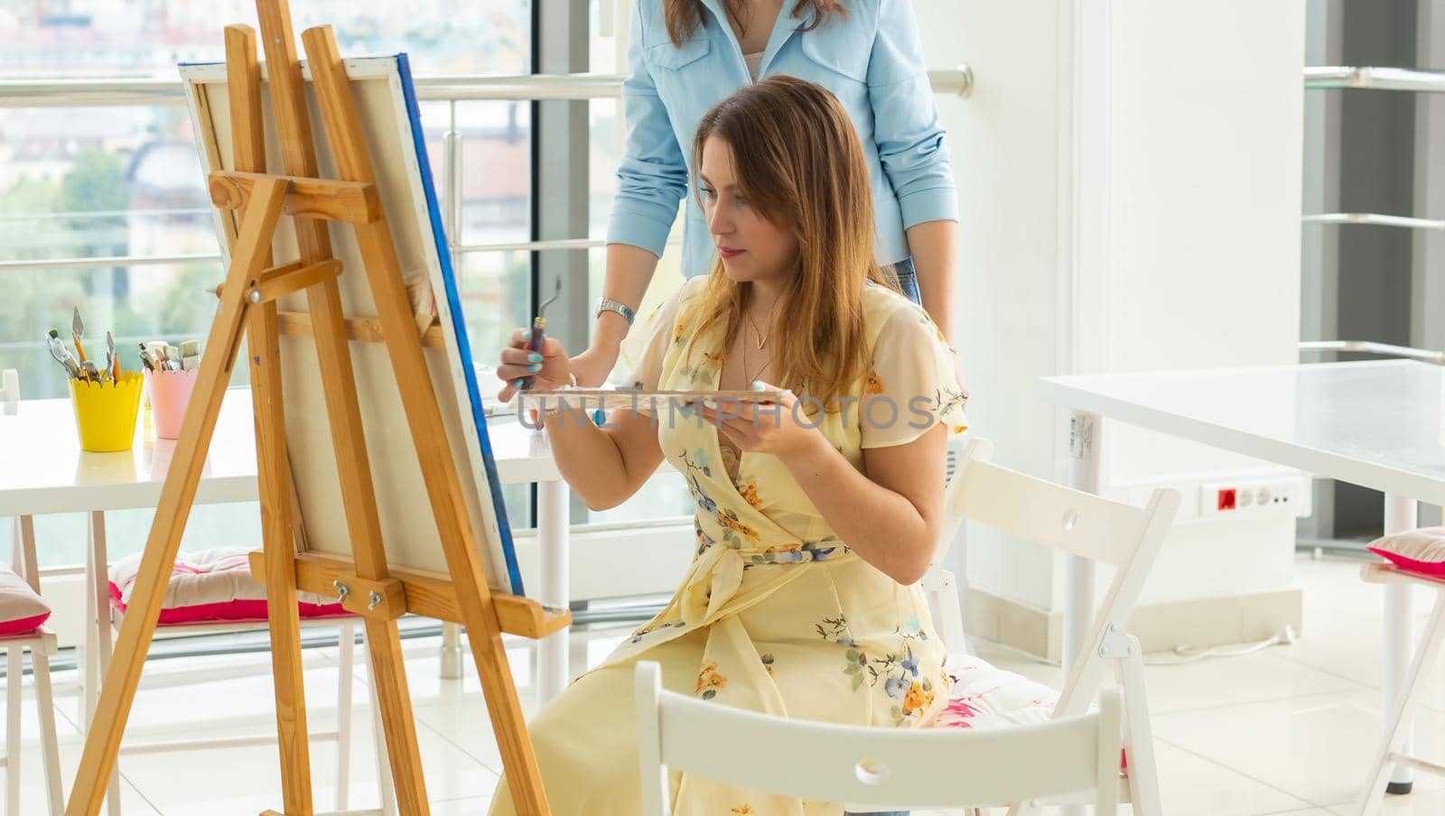 School of art, college of arts, education for group of young students. Happy young woman smiling, girl learning to paint with teacher. by Satura86