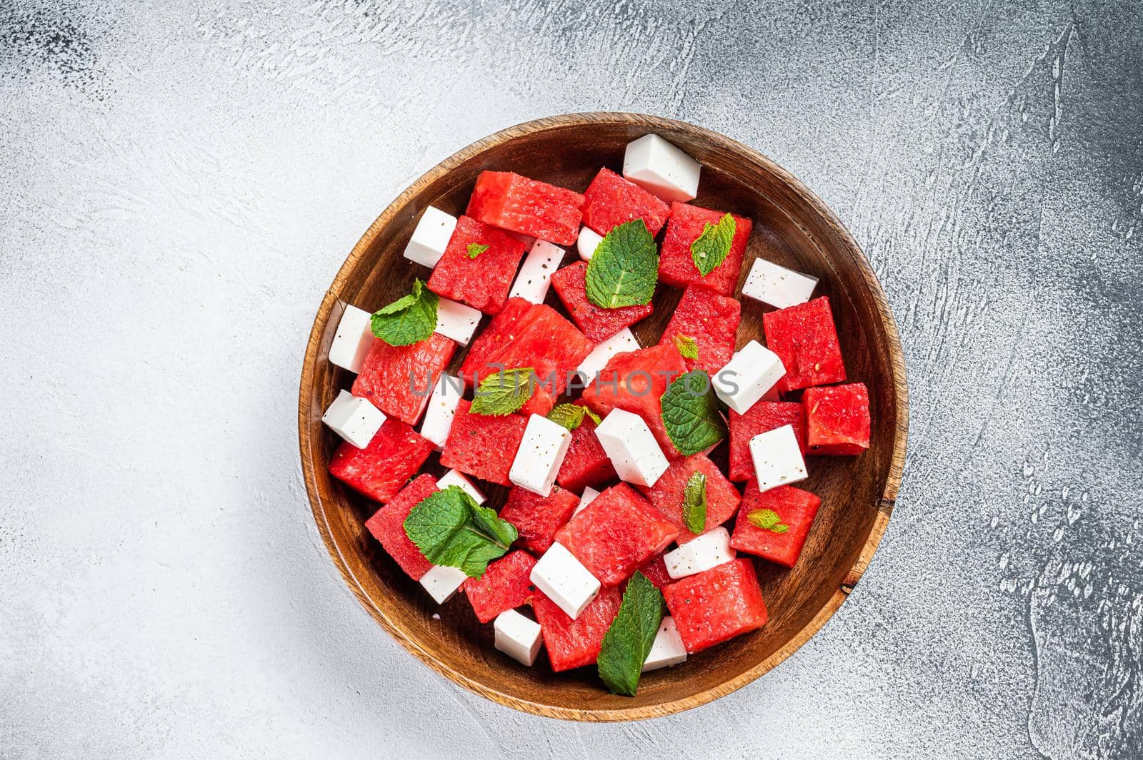 Watermelon Salad with feta cheese in a wooden plate. White background. Top view by Composter