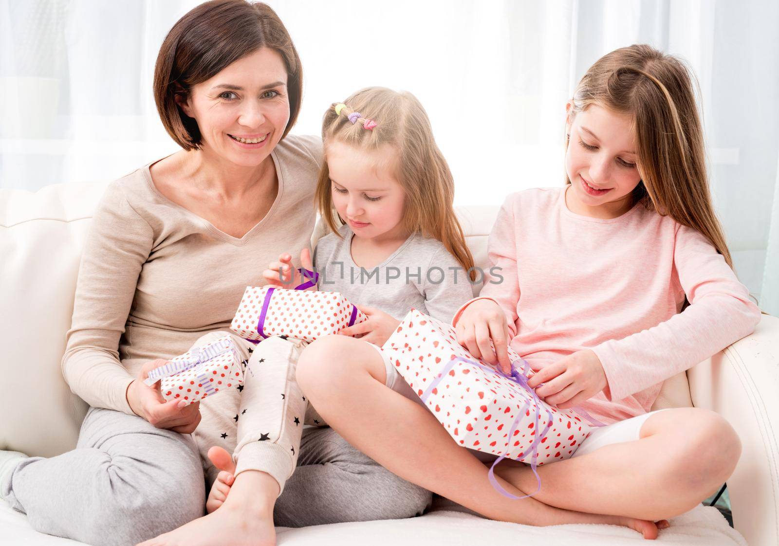Cheerful mom and her beautiful daughters exchanging gifts