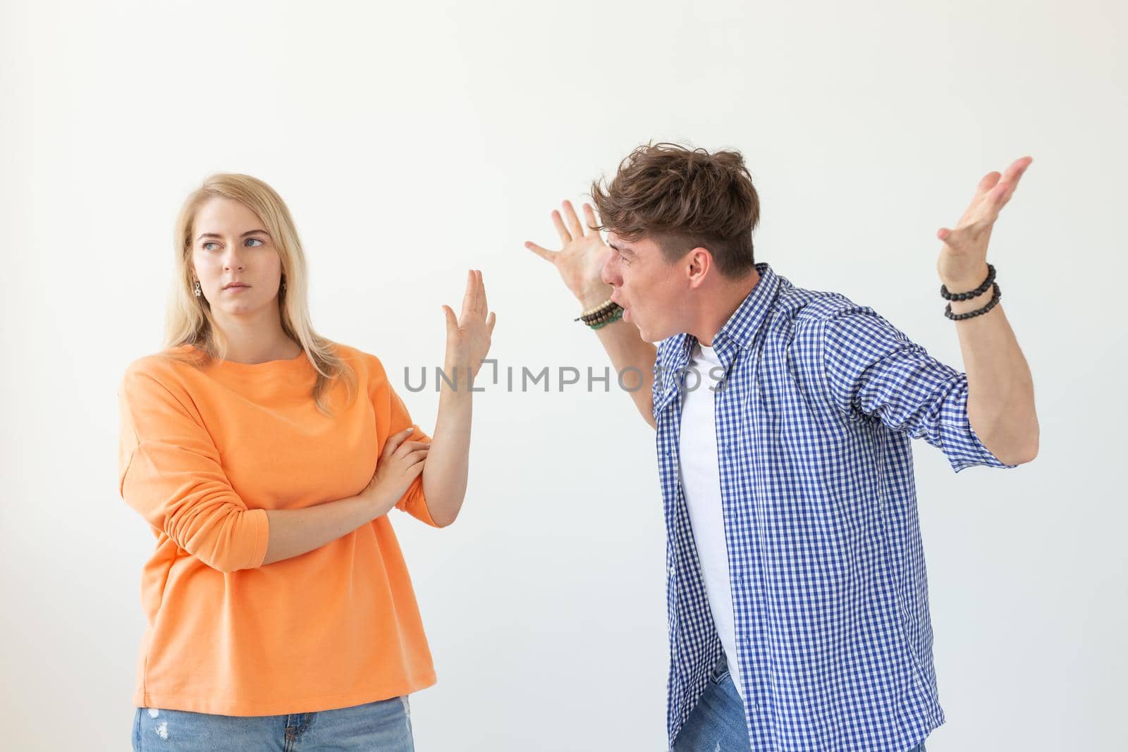 Young hipster guy shouts raising his hands up to his beloved girl showing by hands stop on a white background. Concept of bad relationships and family breakdown