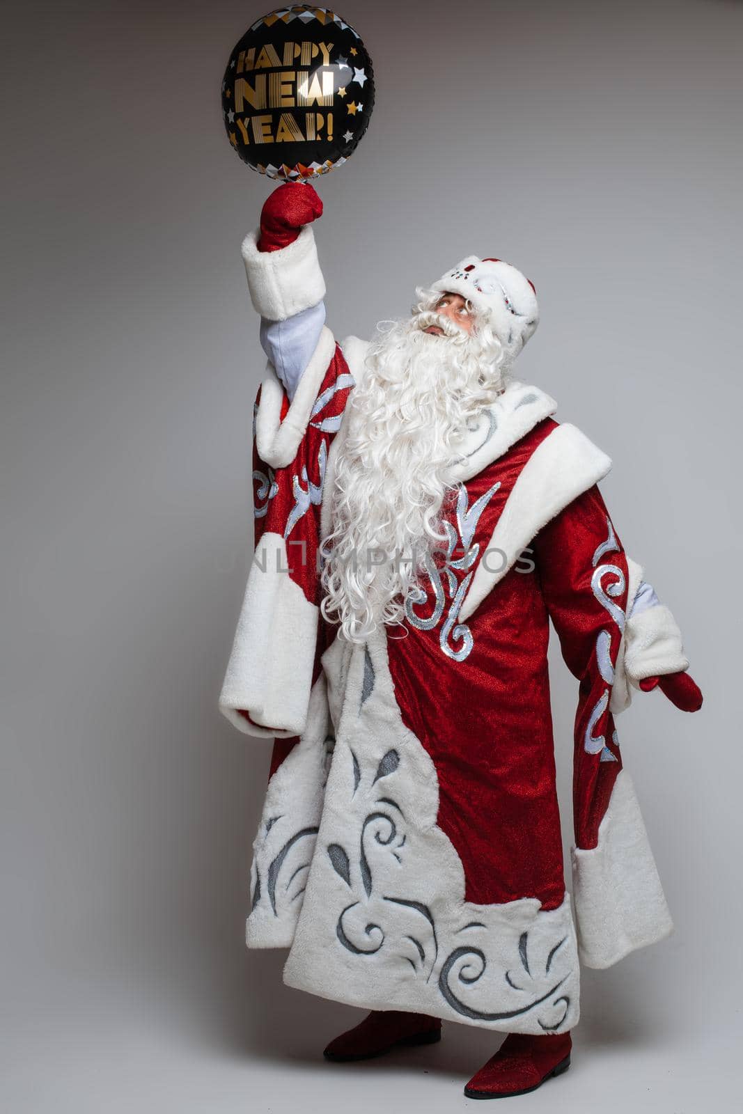 Santa Claus posing with festive balloon on gray studio background, xmas and new year celebration concept. High quality photo