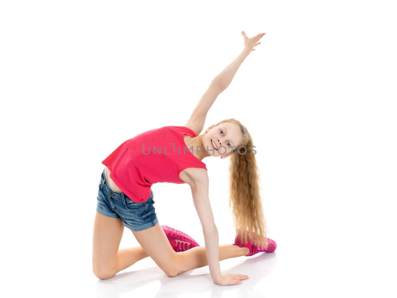 A girl gymnast performs an acrobatic element on the floor. The concept of childhood, sport, healthy lifestyle. Isolated on white background.