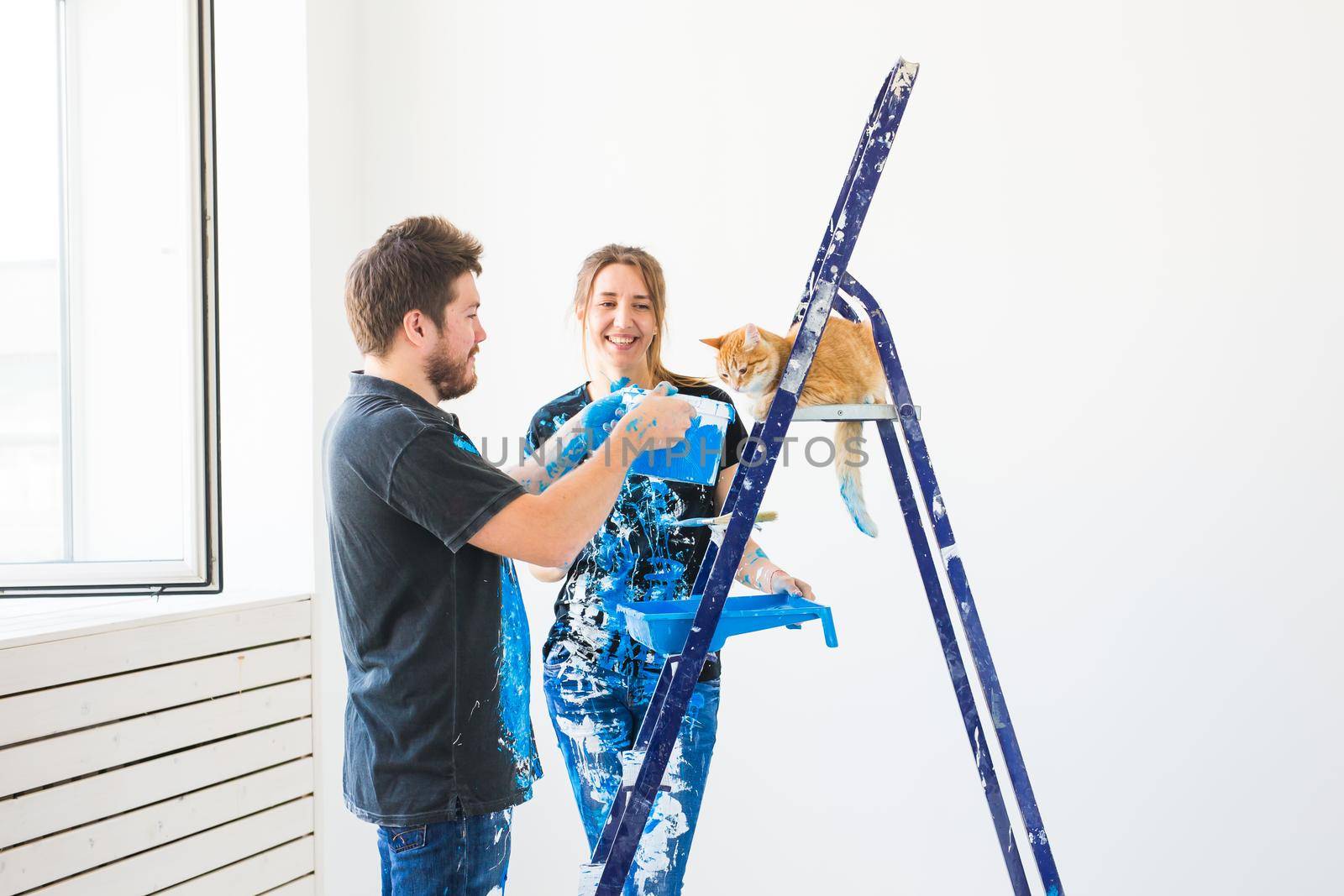 Teamwork and repair concept - young couple with cat doing a renovation in new apartment.