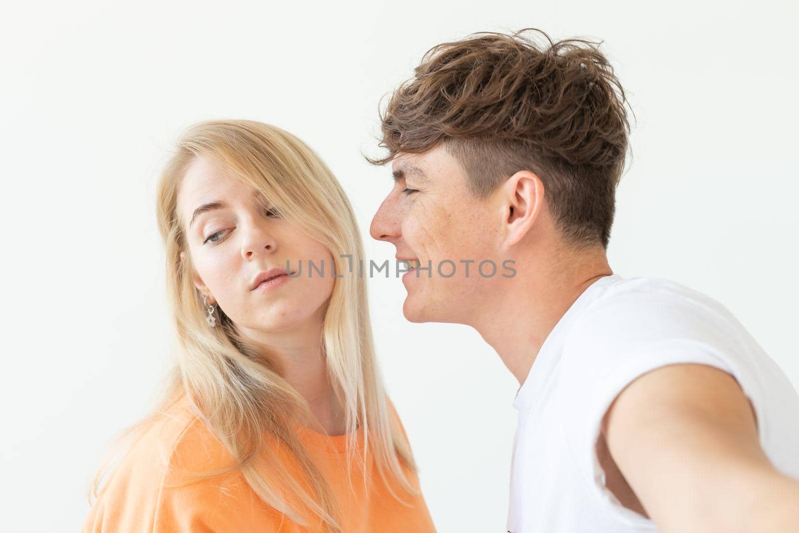 Charming young couple cute blond girl girl take a selfie posing over white background. Concept a young couple of teenagers or millennials In love. by Satura86