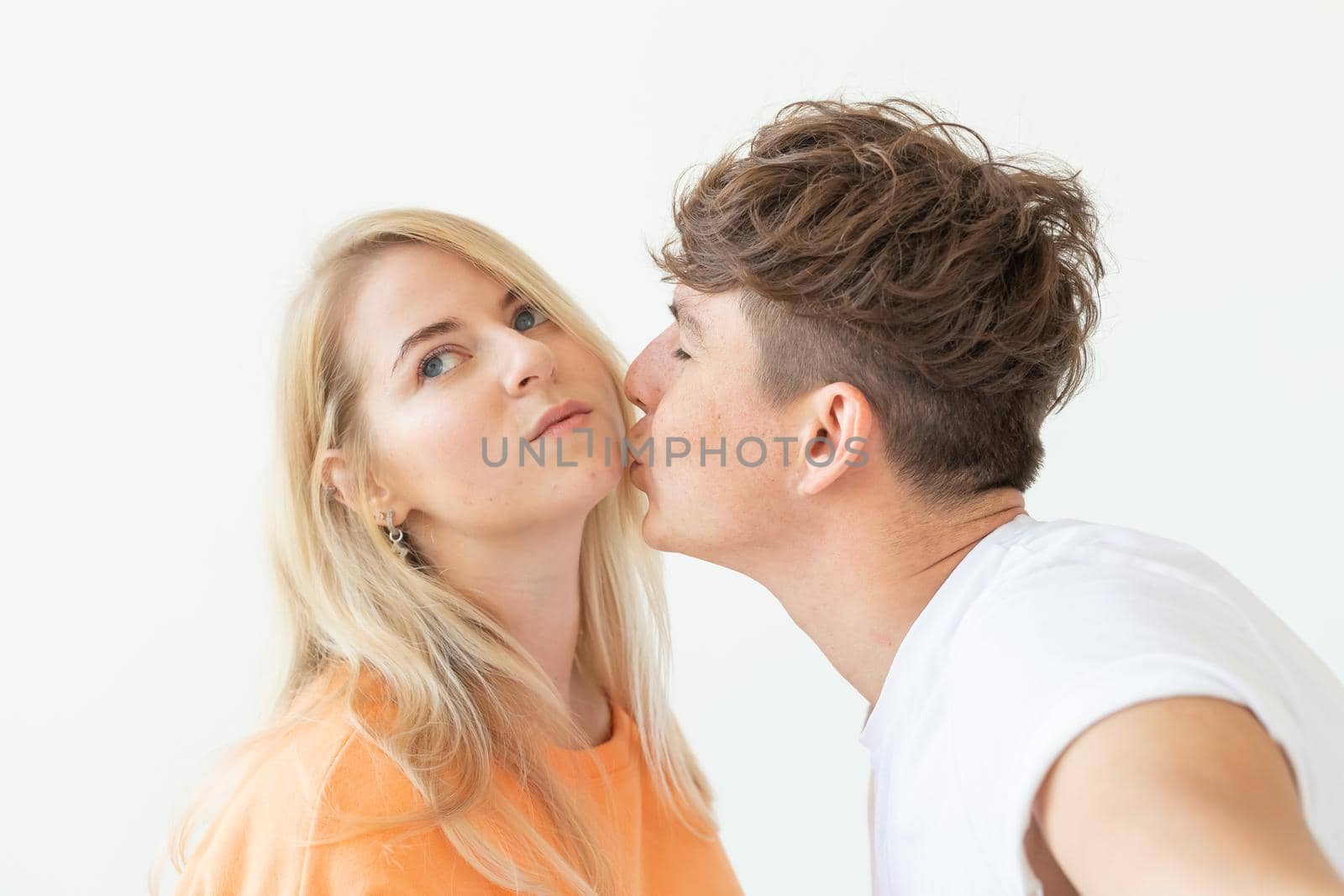 Charming young couple cute blond girl girl take a selfie posing over white background. Concept a young couple of teenagers or millennials In love. by Satura86