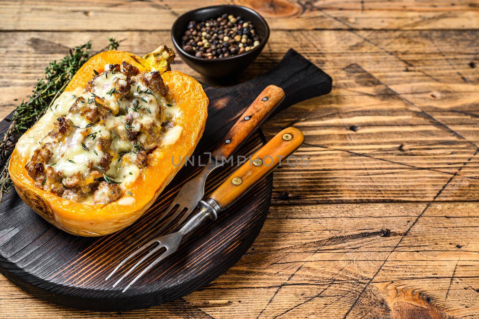 Cooked pumpkin stuffed with ground mince meat, vegetables and herbs. wooden background. Top view. Copy space.