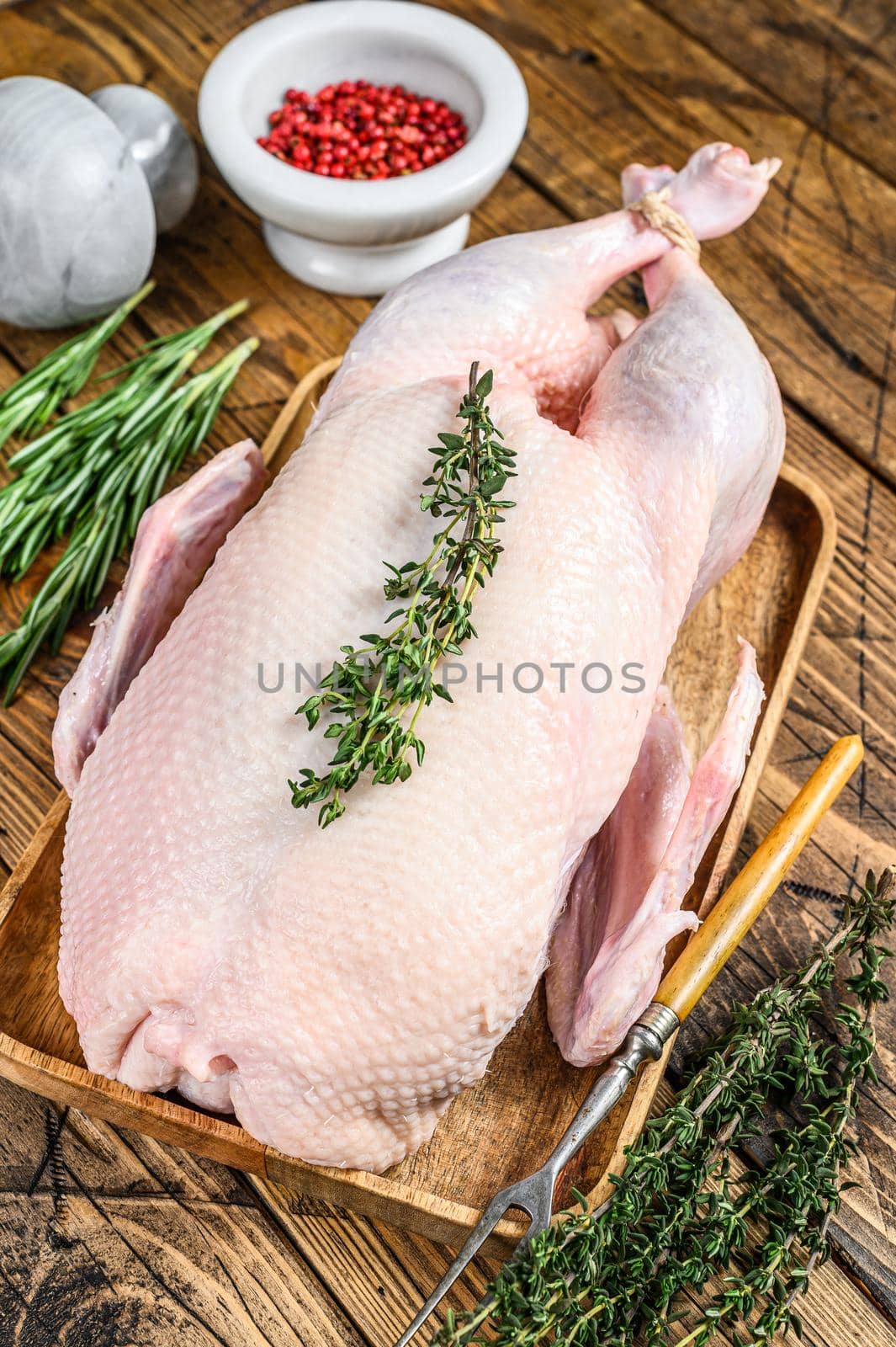 Raw whole farm duck with herbs. wooden background. Top view.