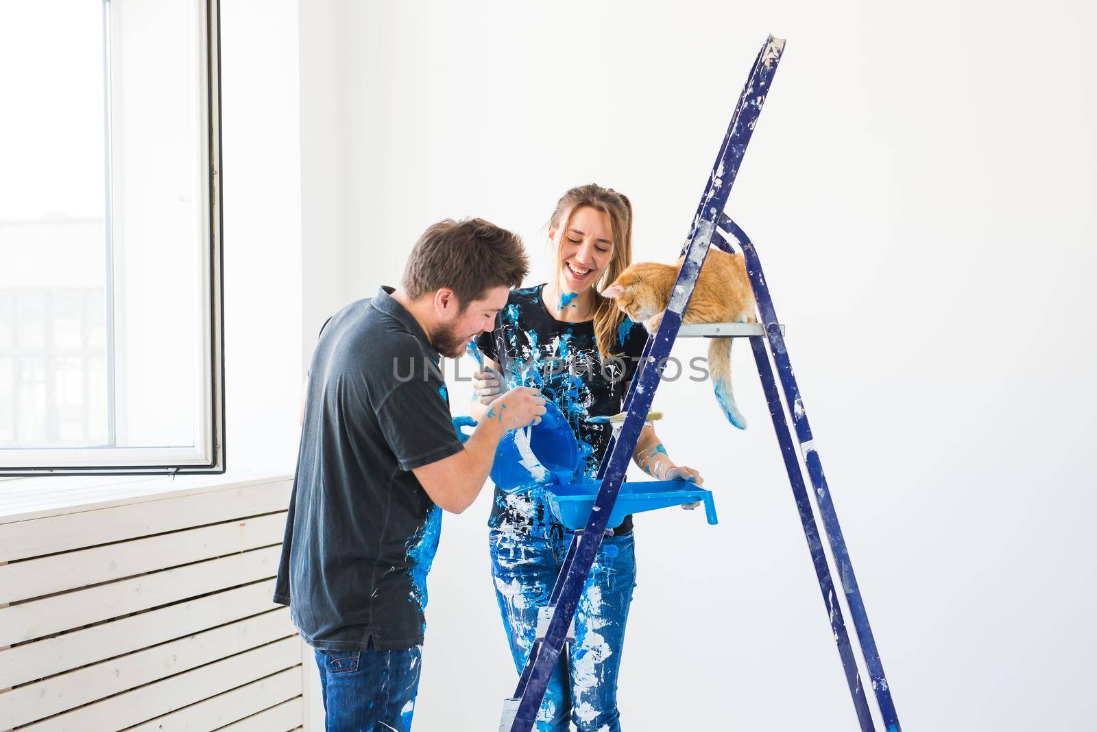 Teamwork and repair concept - young couple with cat doing a renovation in new apartment by Satura86