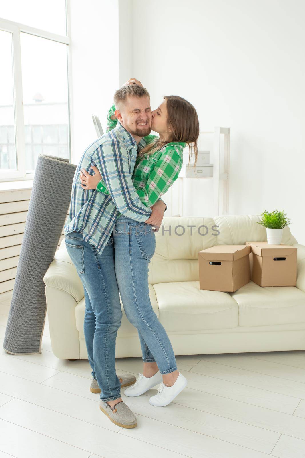 Loving young couple embracing rejoicing in moving to their new home. The concept of moving and housewarming of young family. by Satura86