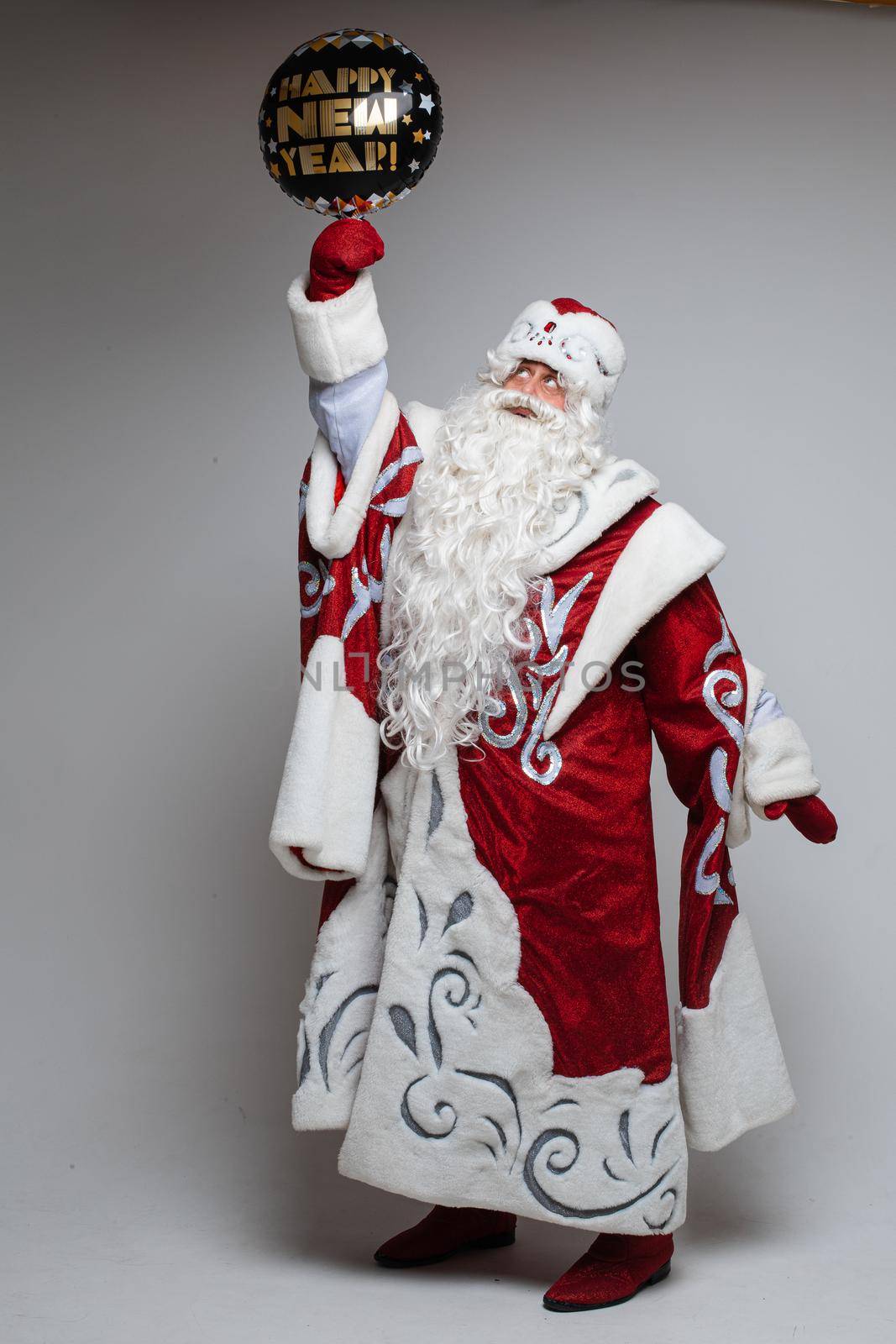 father frost with long beard holds a black christmas baloon, picture isolated on grey background