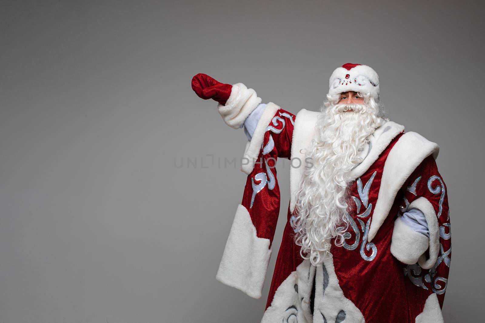 father frost with long beard points to the side, picture isolated on light grey background