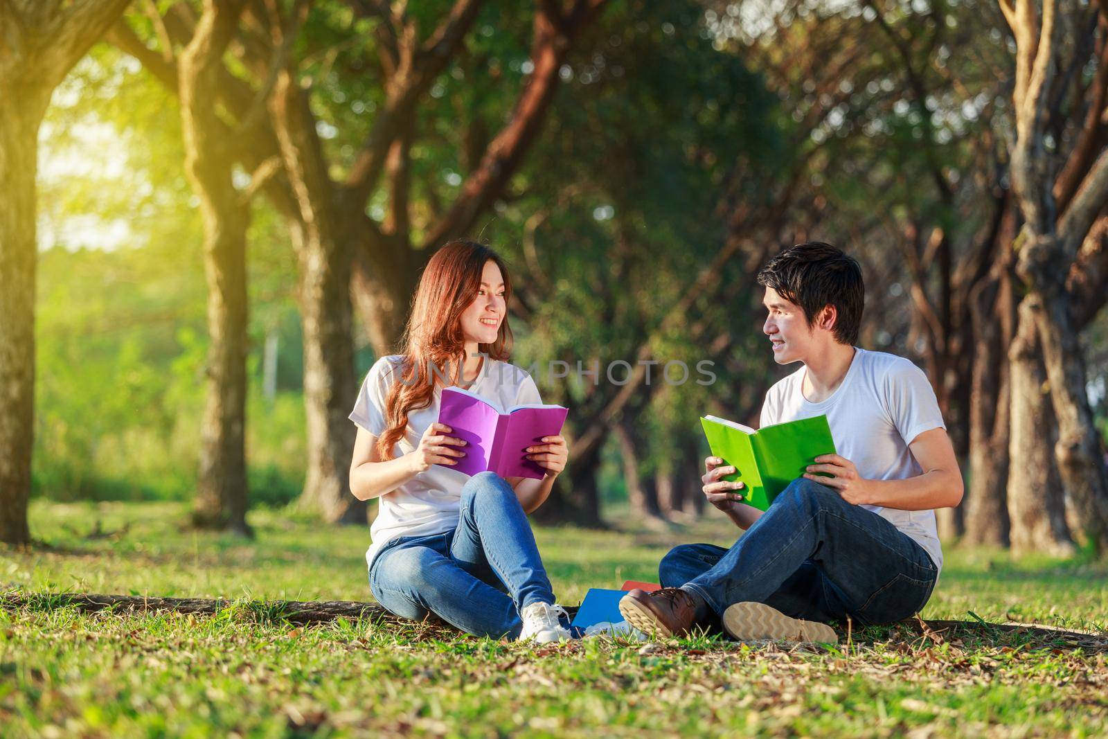 man and woman sitting and reading a book in the park